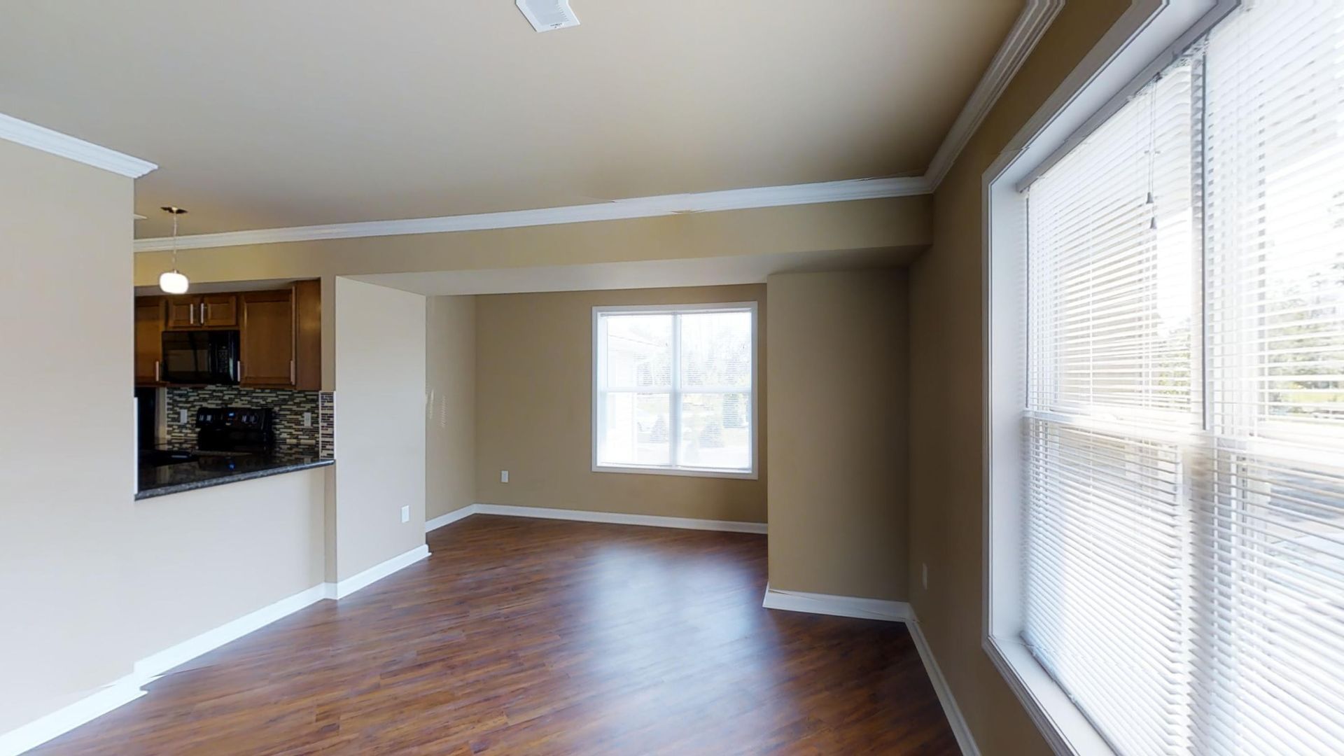 An empty living room with hardwood floors and two windows.