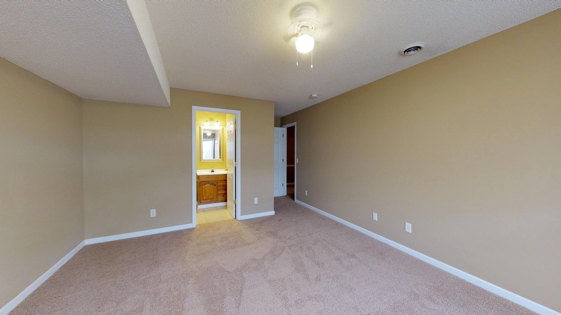 An empty bedroom with a ceiling fan and a bathroom.