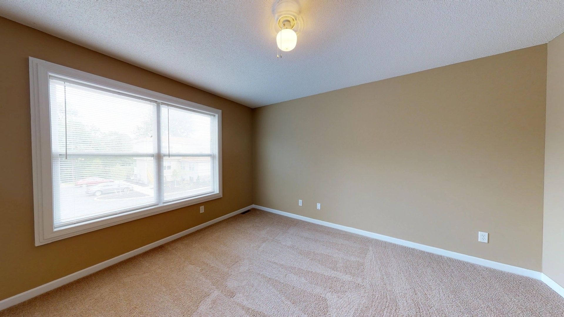 An empty room with two windows and a carpeted floor.