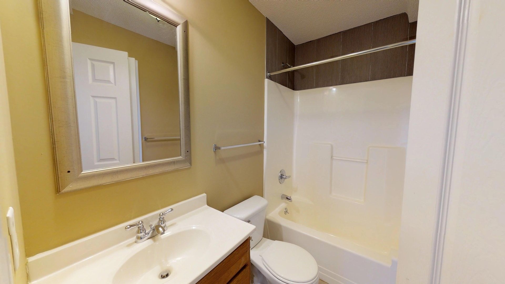 A bathroom with a toilet , sink , mirror and bathtub.