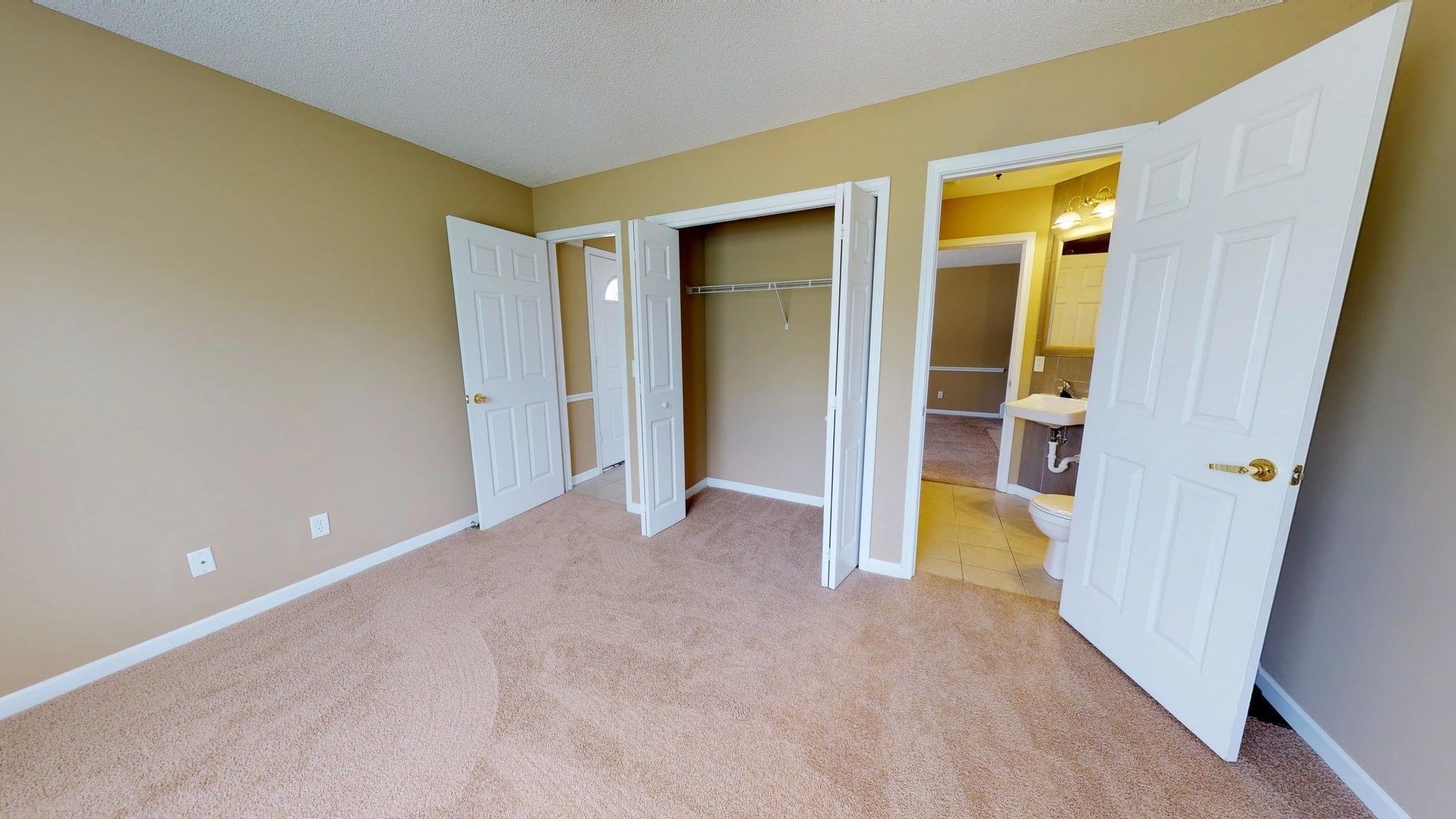 An empty bedroom with a walk in closet and a bathroom.