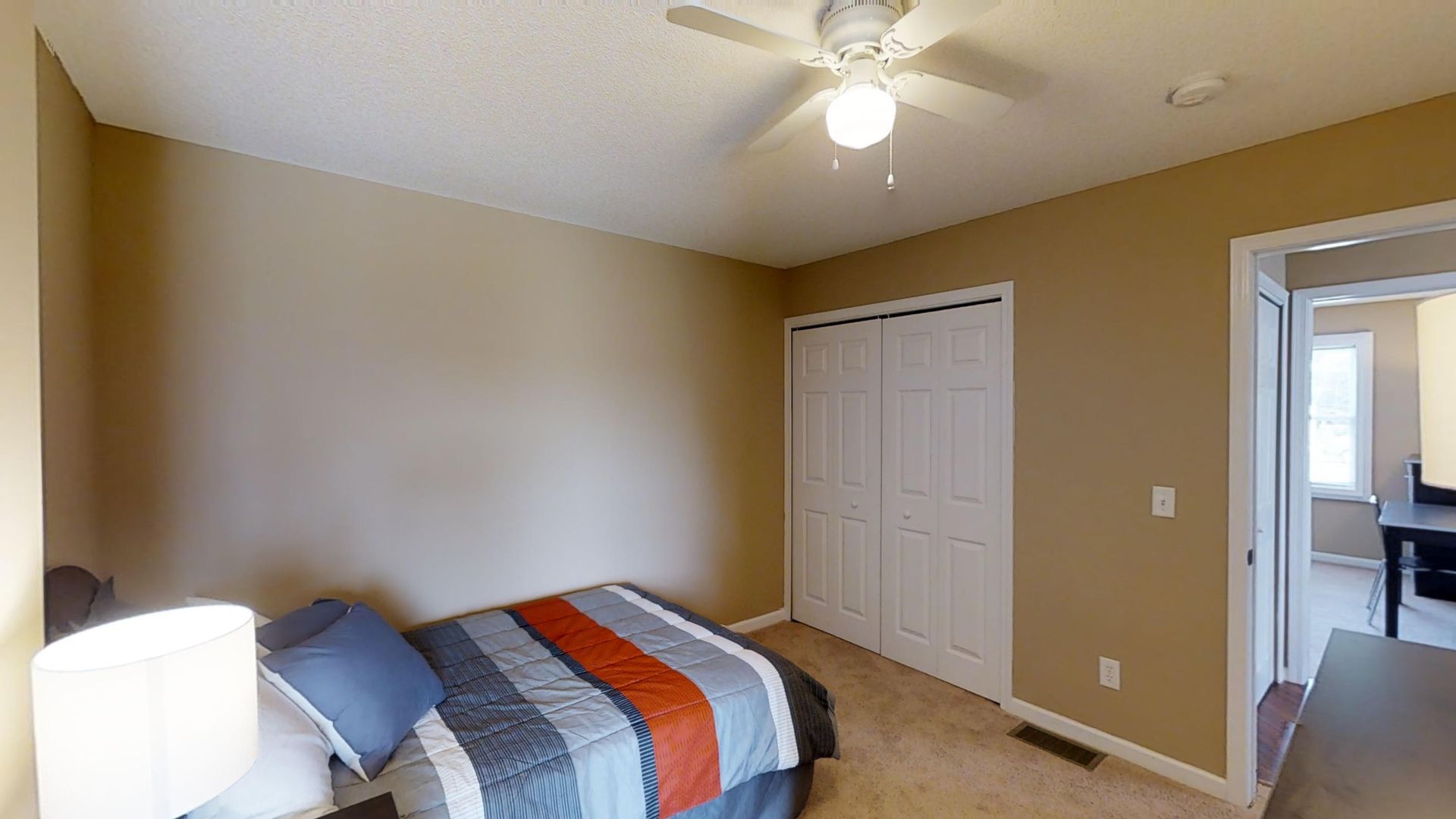 A bedroom with a bed and a ceiling fan.