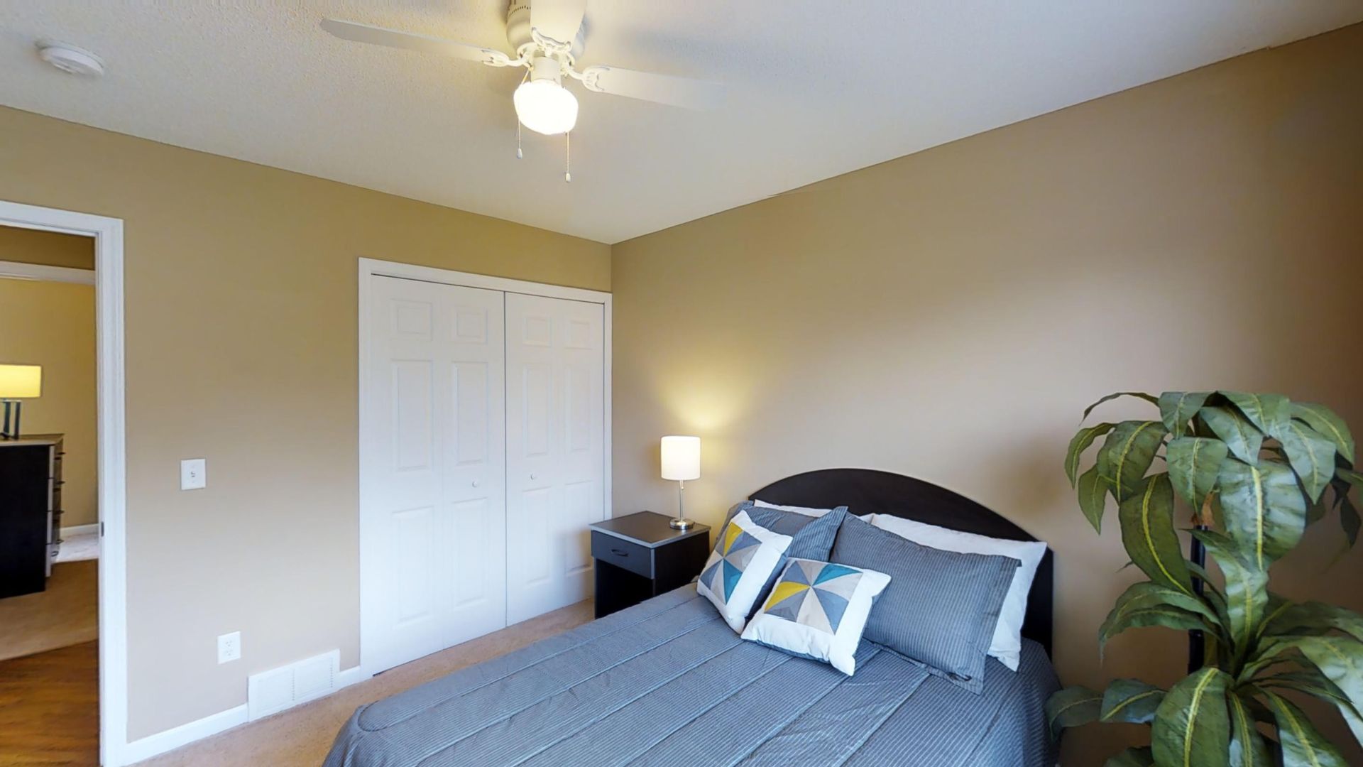 A bedroom with a bed and a ceiling fan.