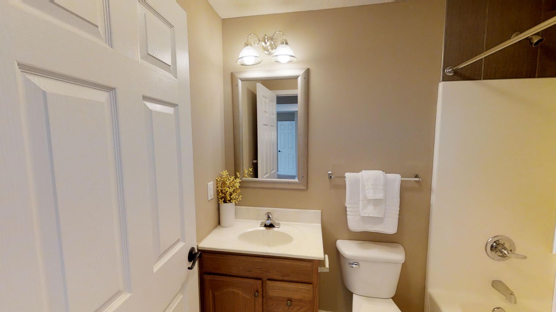 A bathroom with a toilet , sink , mirror and bathtub.