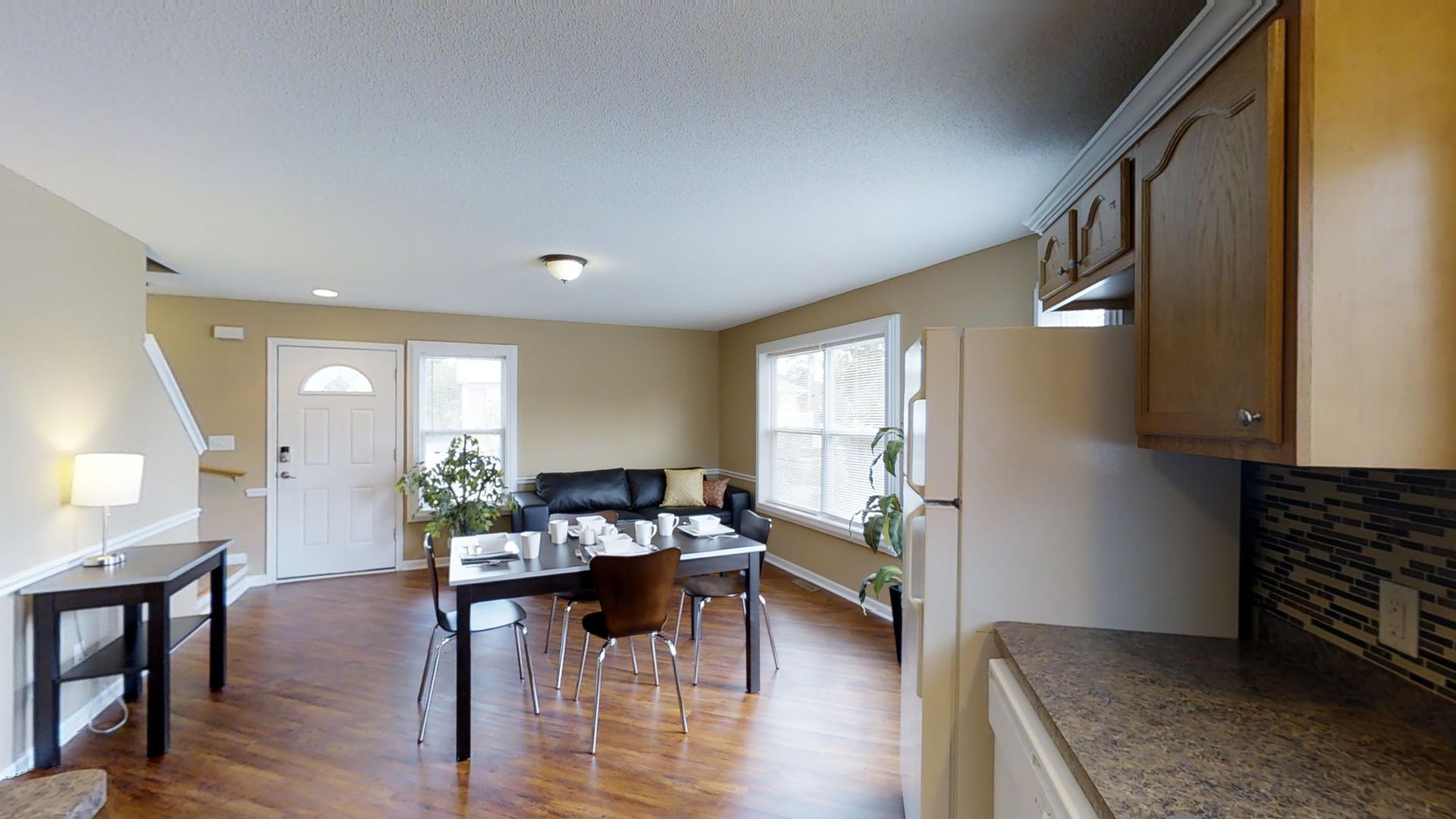 A living room with a couch , table , chairs and a refrigerator.