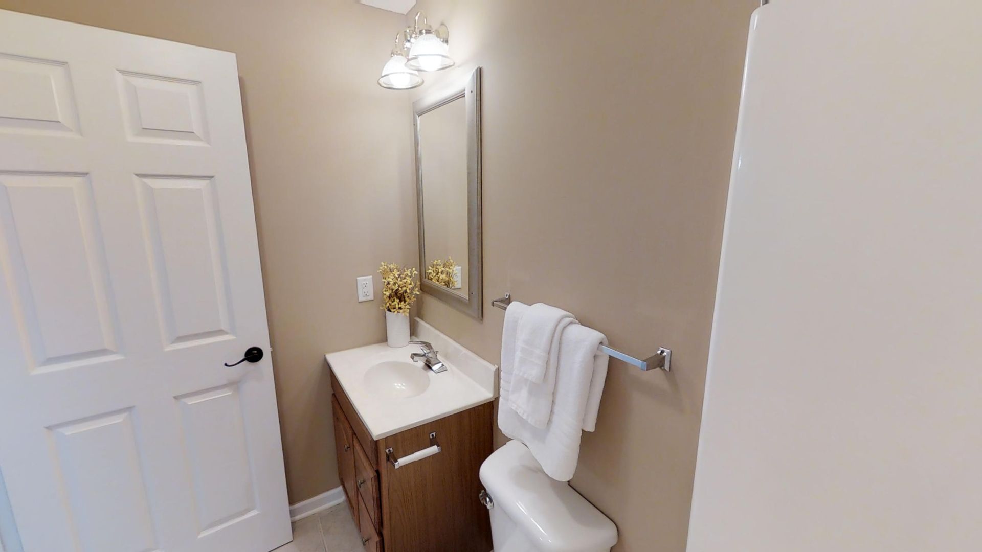 A bathroom with a sink , toilet , mirror and towel rack.