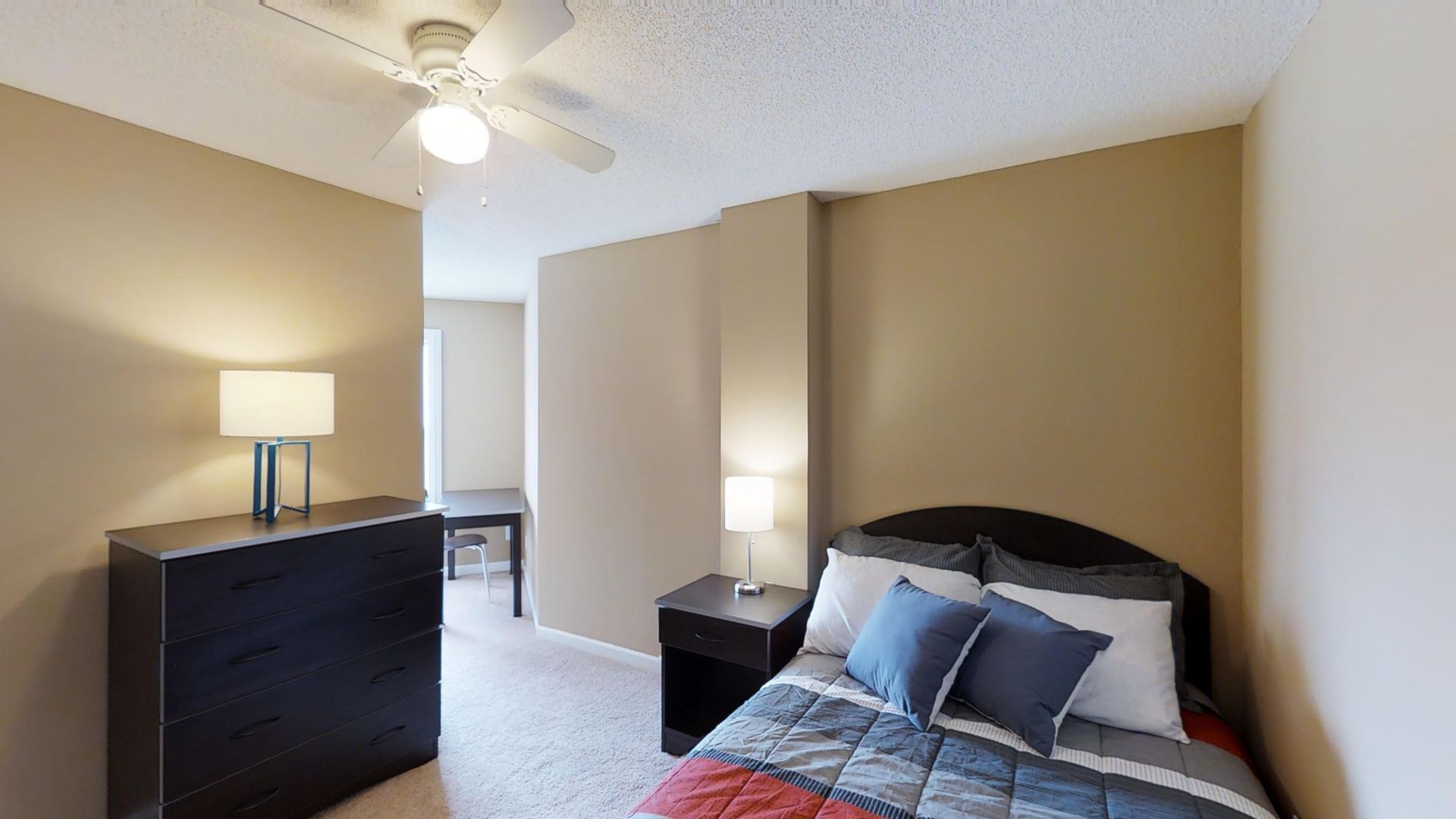 A bedroom with a bed , nightstand , dresser and ceiling fan.