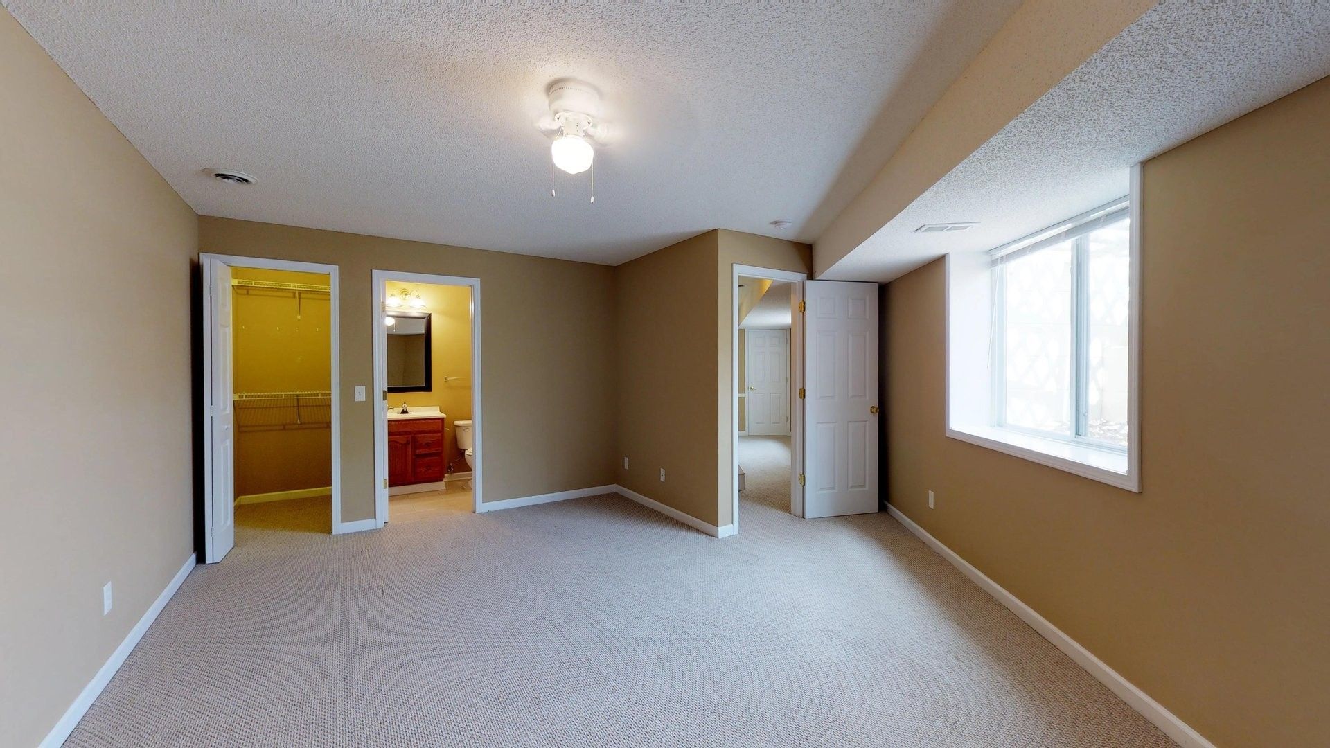 An empty room with a carpeted floor and a window.