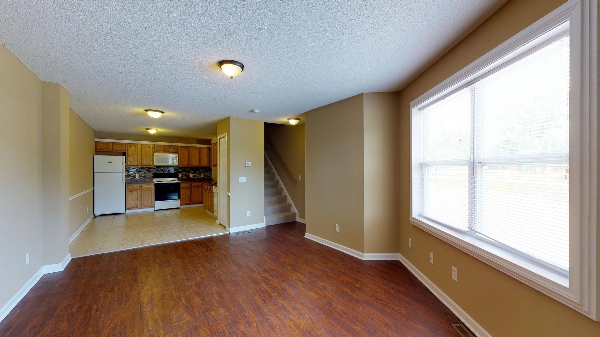 An empty living room with hardwood floors and a large window