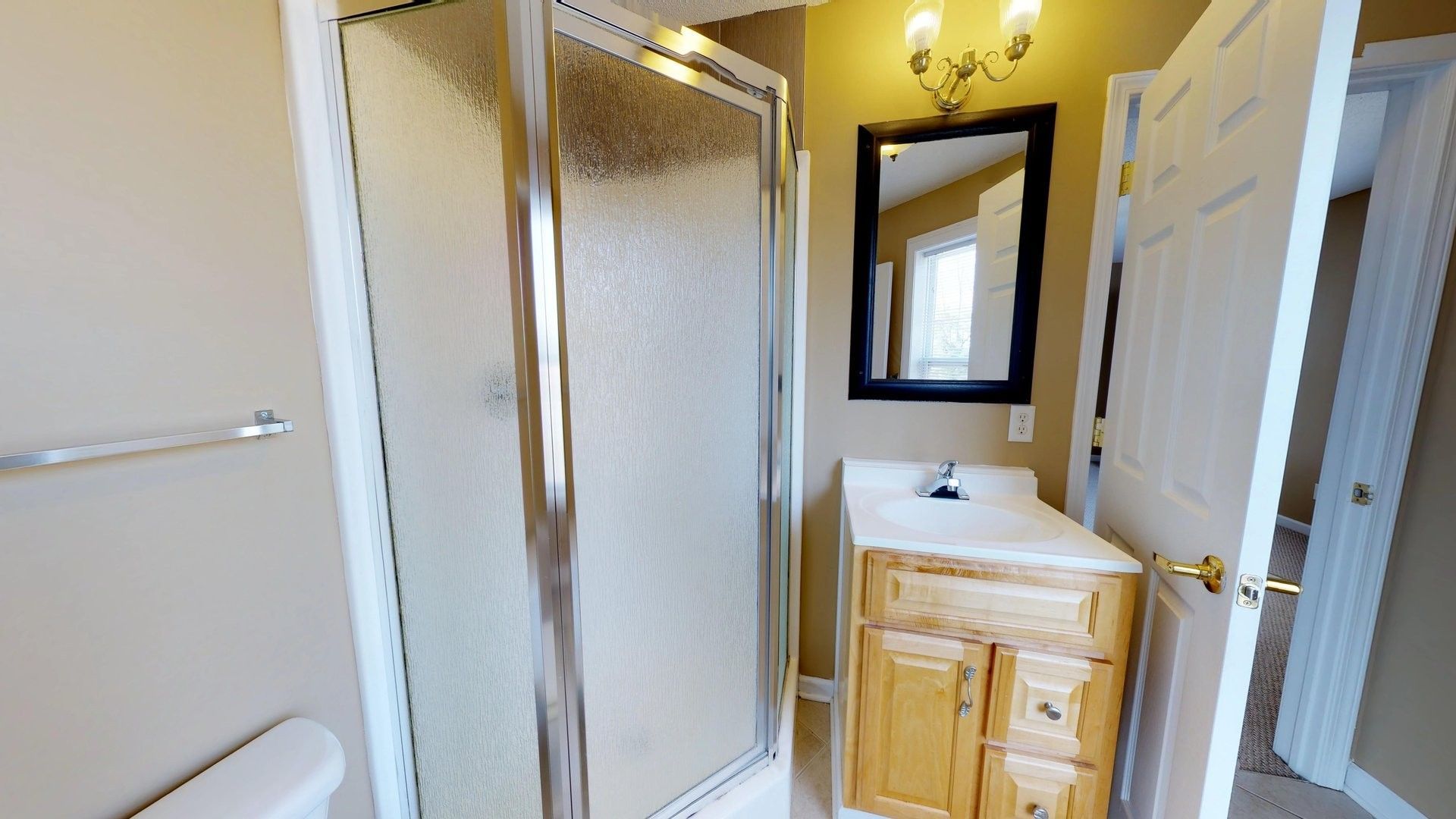 A bathroom with a sink , toilet , shower and mirror.