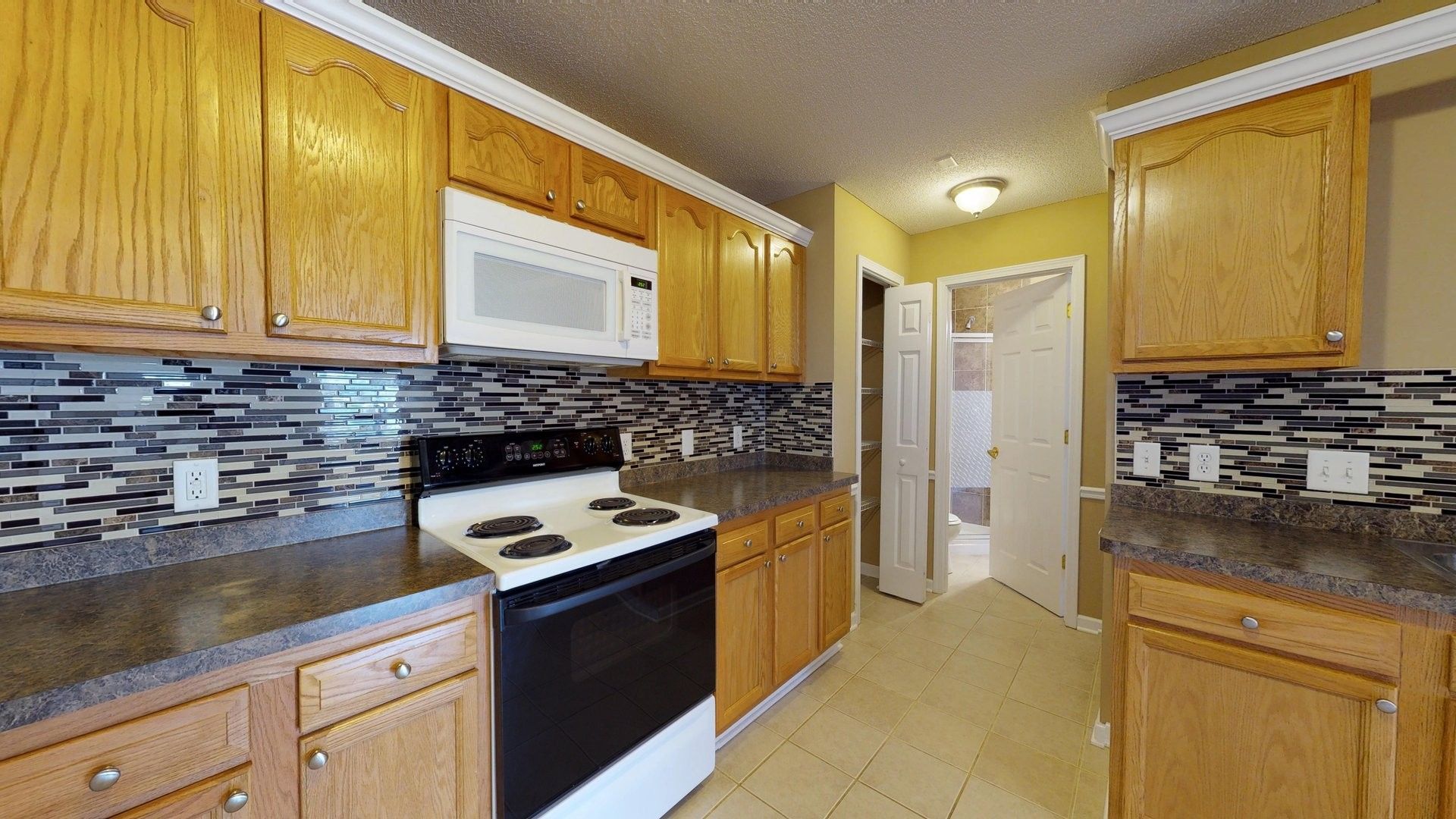 A kitchen with wooden cabinets , a stove and a microwave.