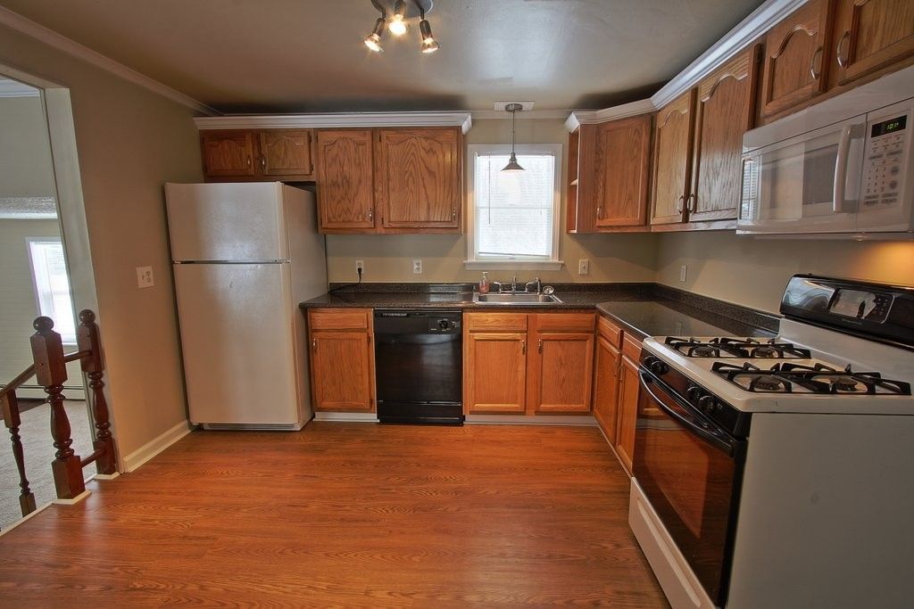 A kitchen with a stove , refrigerator and microwave