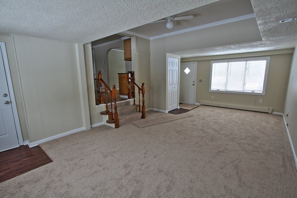 An empty living room with a staircase leading to the second floor.