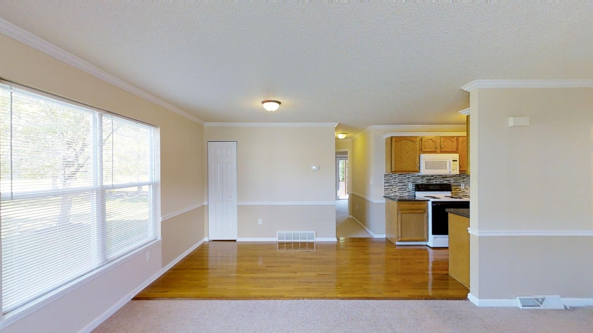 An empty living room with hardwood floors and white walls