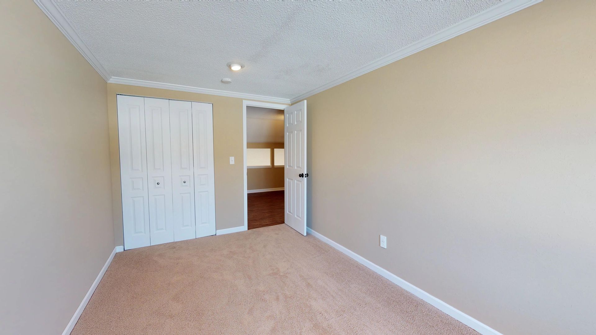 An empty bedroom with a carpeted floor and a closet.