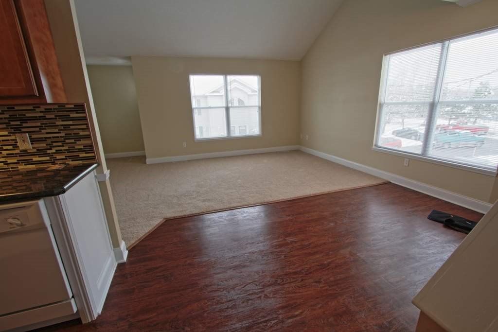 An empty living room with hardwood floors and a stove.