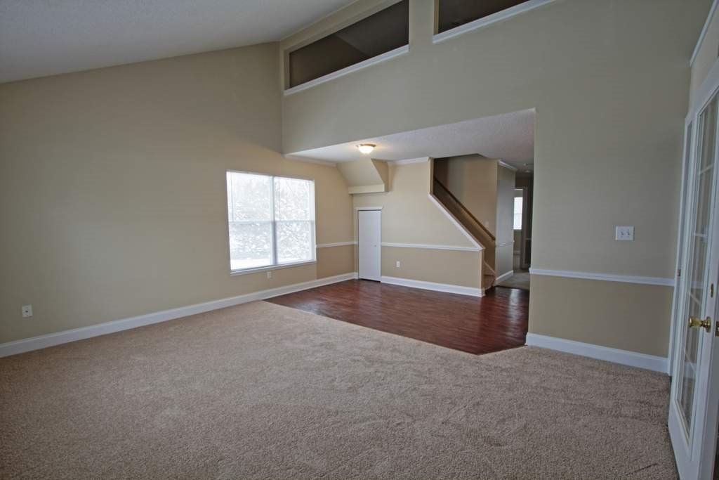 An empty living room with hardwood floors and a staircase.