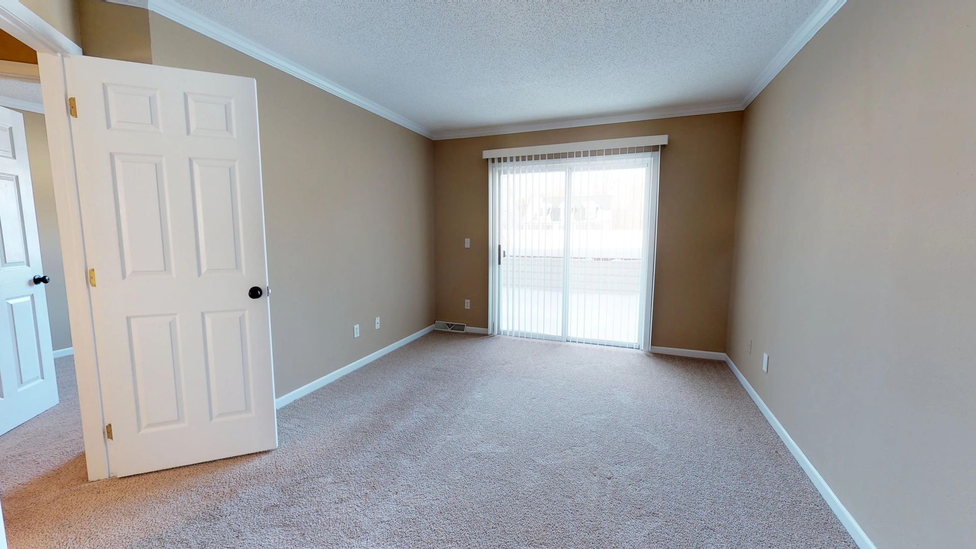 An empty living room with a sliding glass door and a balcony.