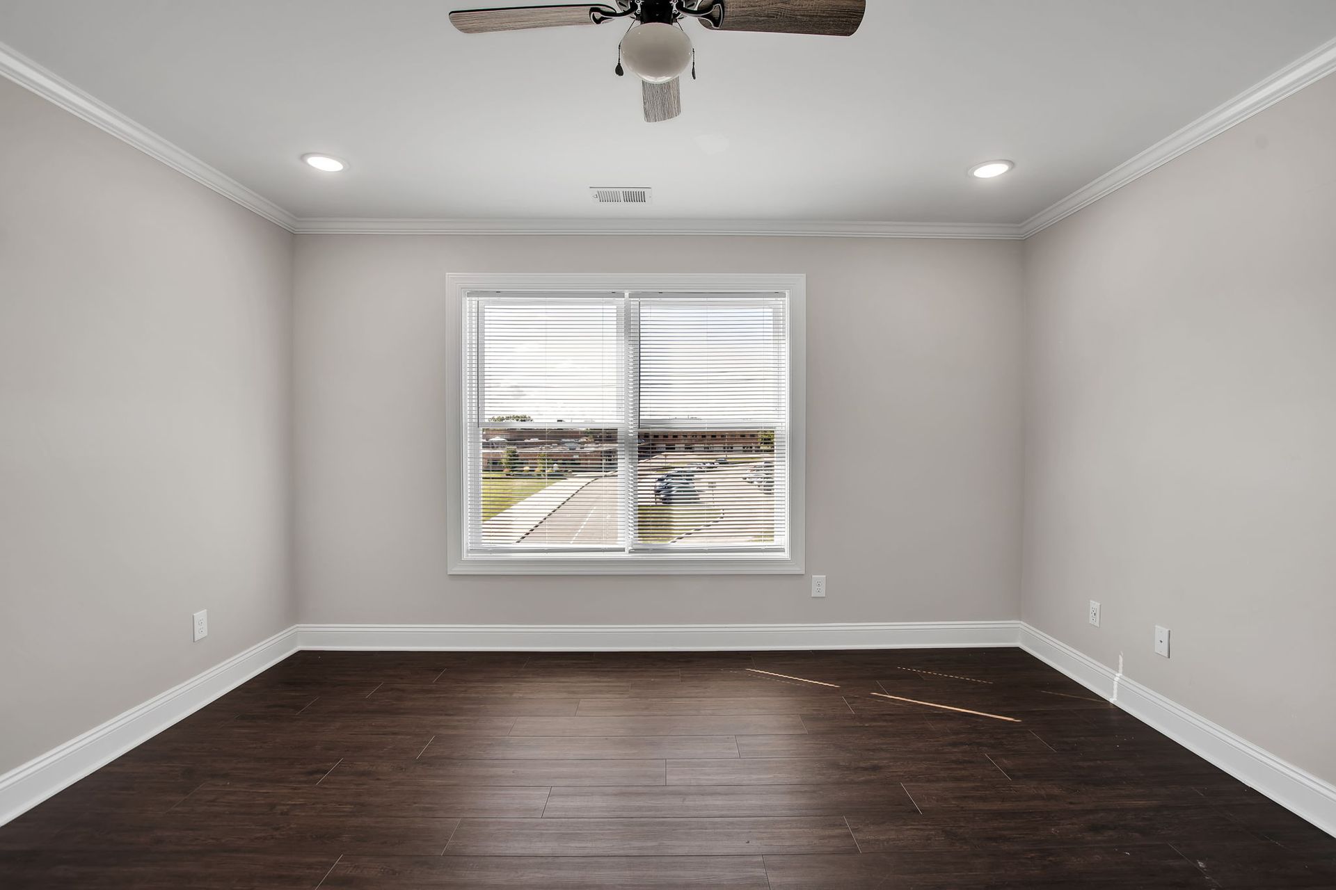 Spacious bedroom with large window, ceiling fan, and natural light
