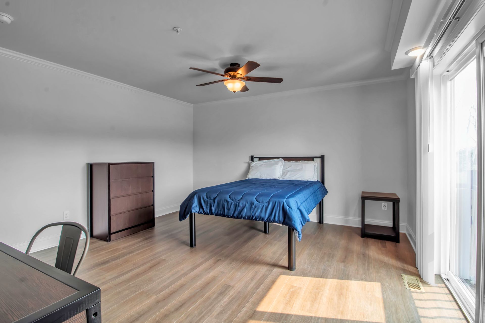 There is a bed in the middle of the room with a ceiling fan.