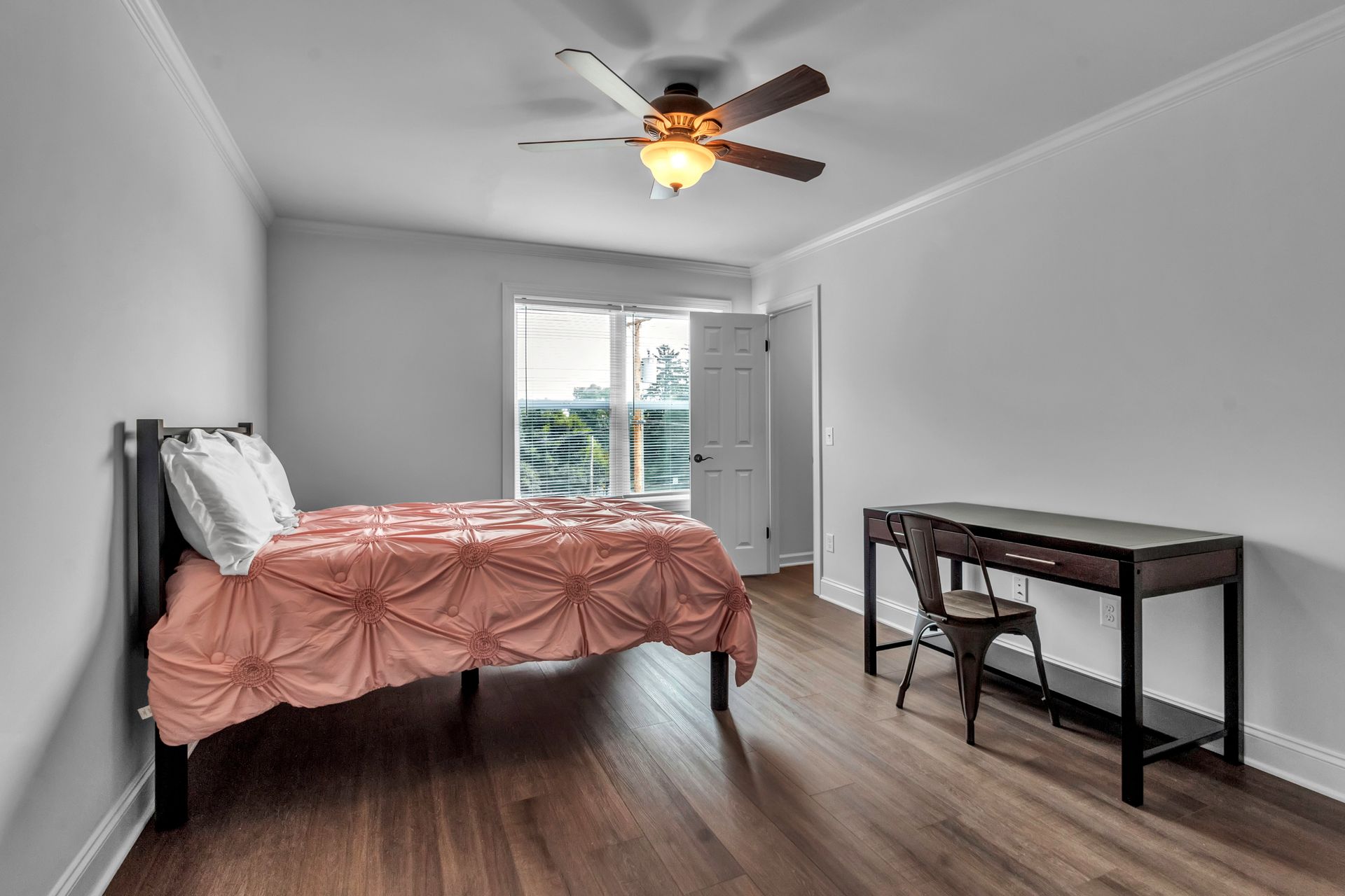 A bedroom with a bed , desk and ceiling fan.