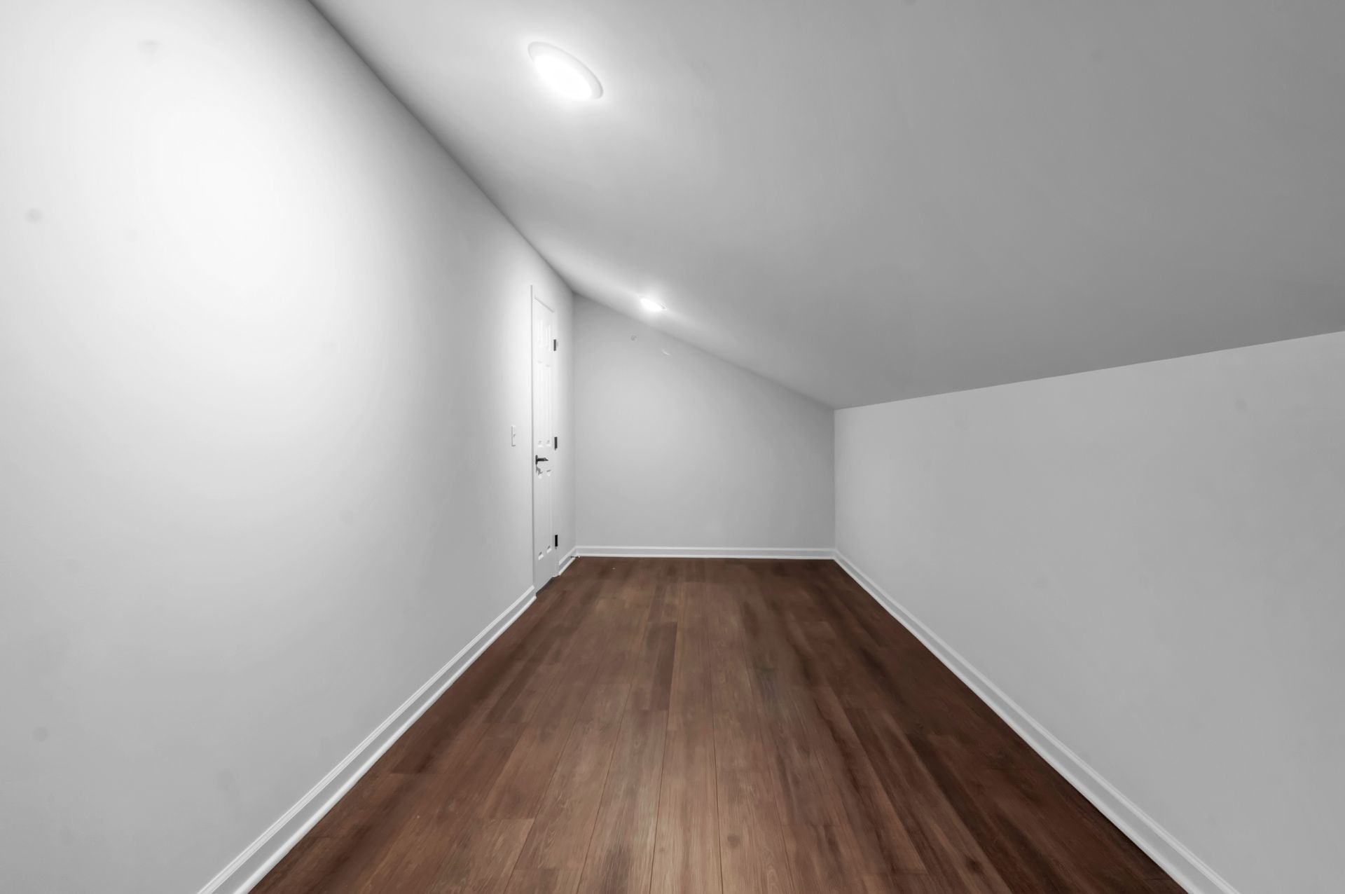 An empty hallway with a wooden floor and white walls.