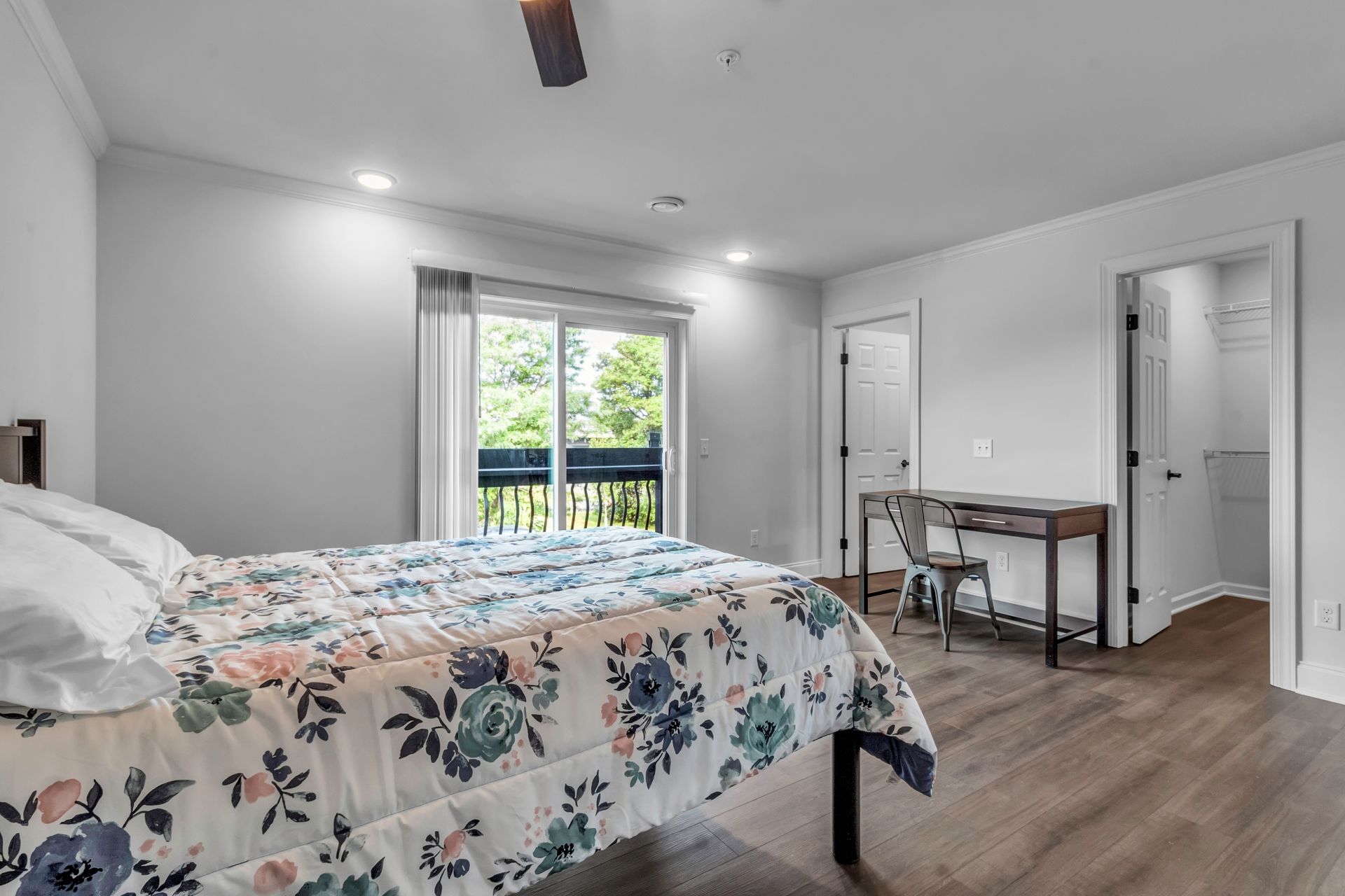 A bedroom with a bed , desk , chair and sliding glass doors.