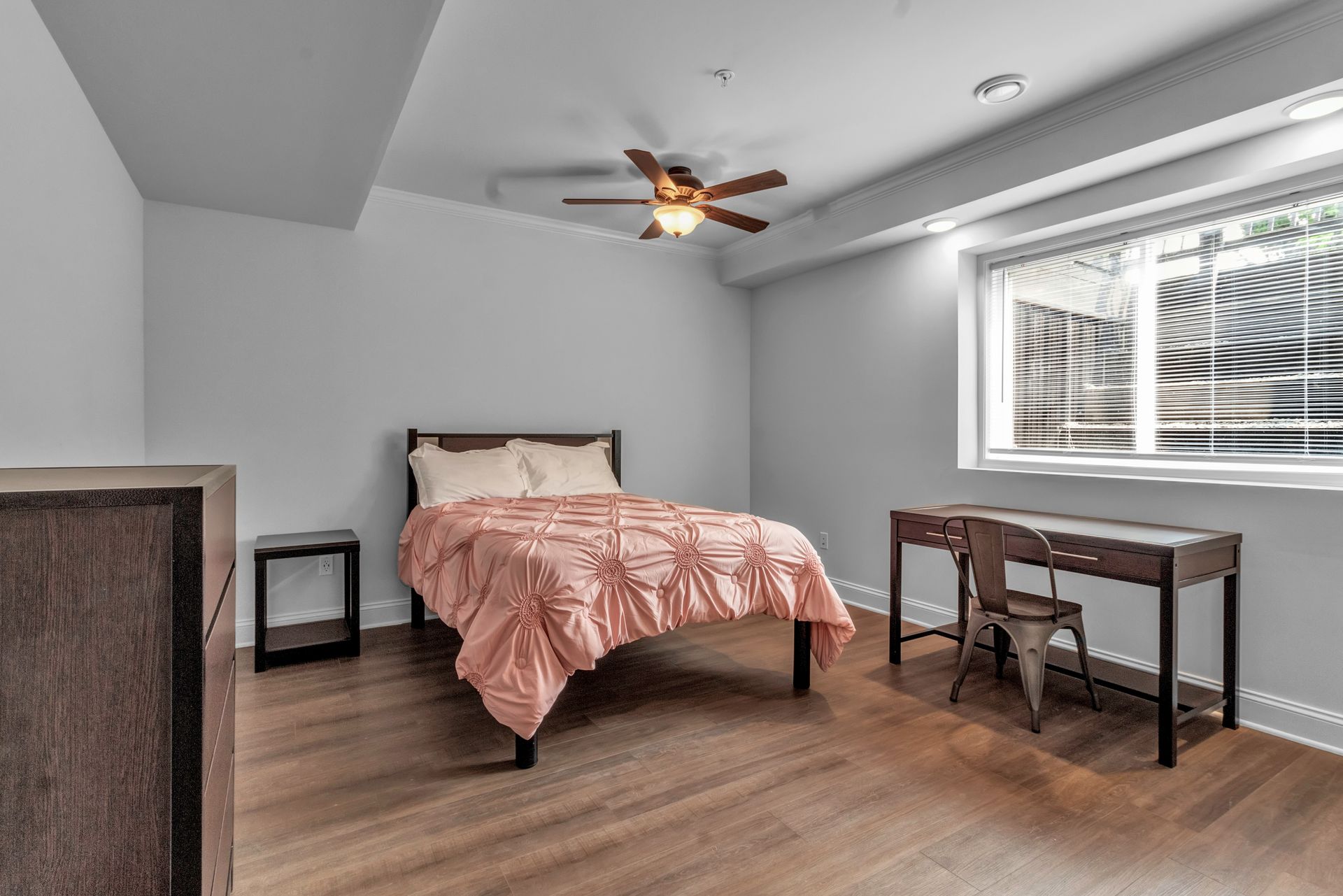 A bedroom with a bed , desk , chair and ceiling fan.