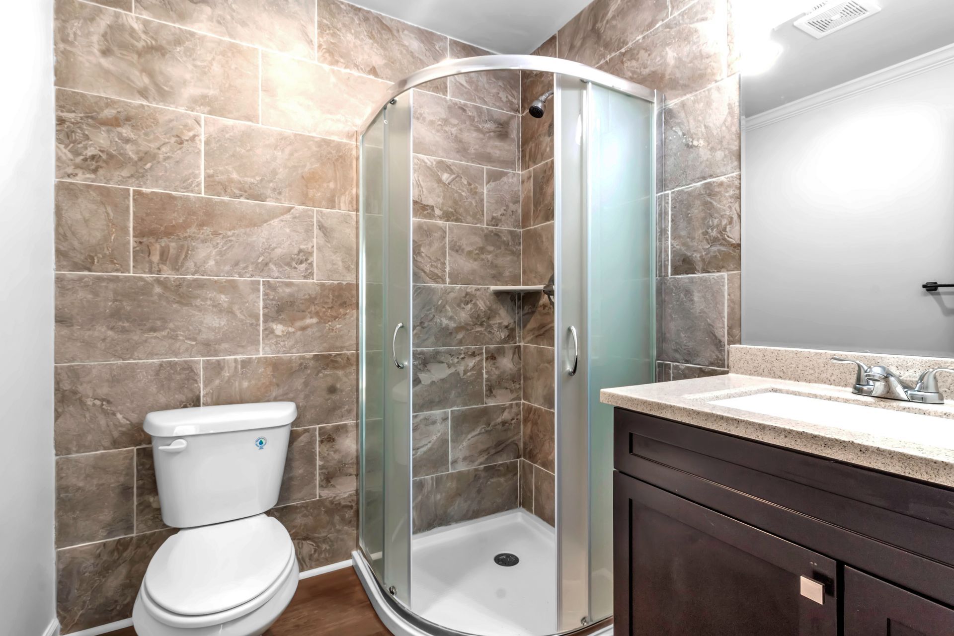 A bathroom with a toilet , sink and shower stall.