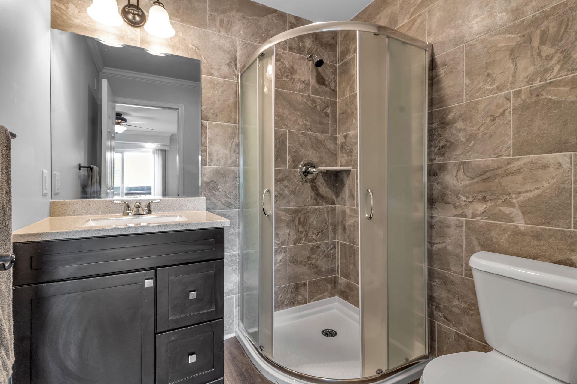 A bathroom with a toilet , sink , shower and mirror.