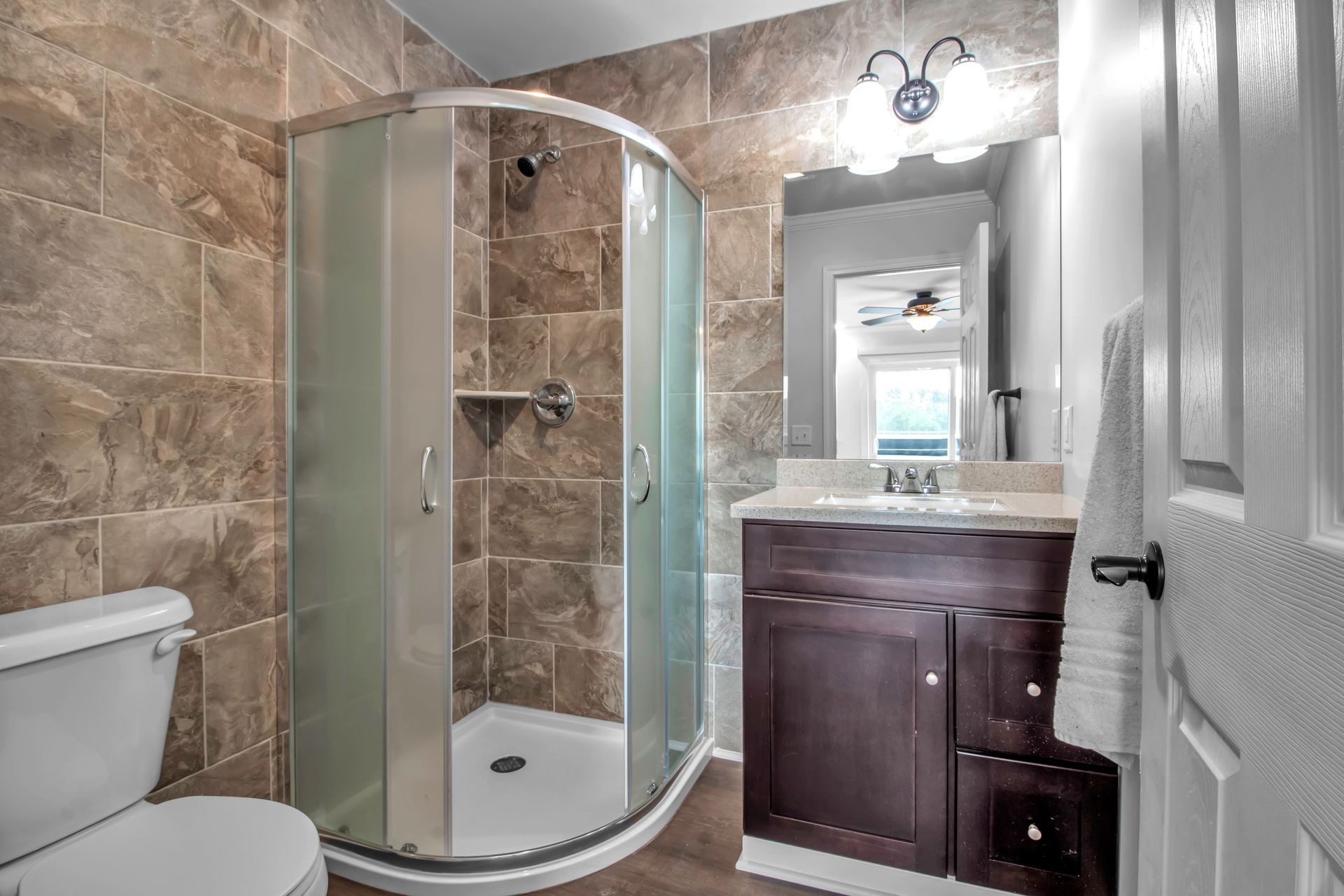 A bathroom with a toilet , sink , shower and mirror.