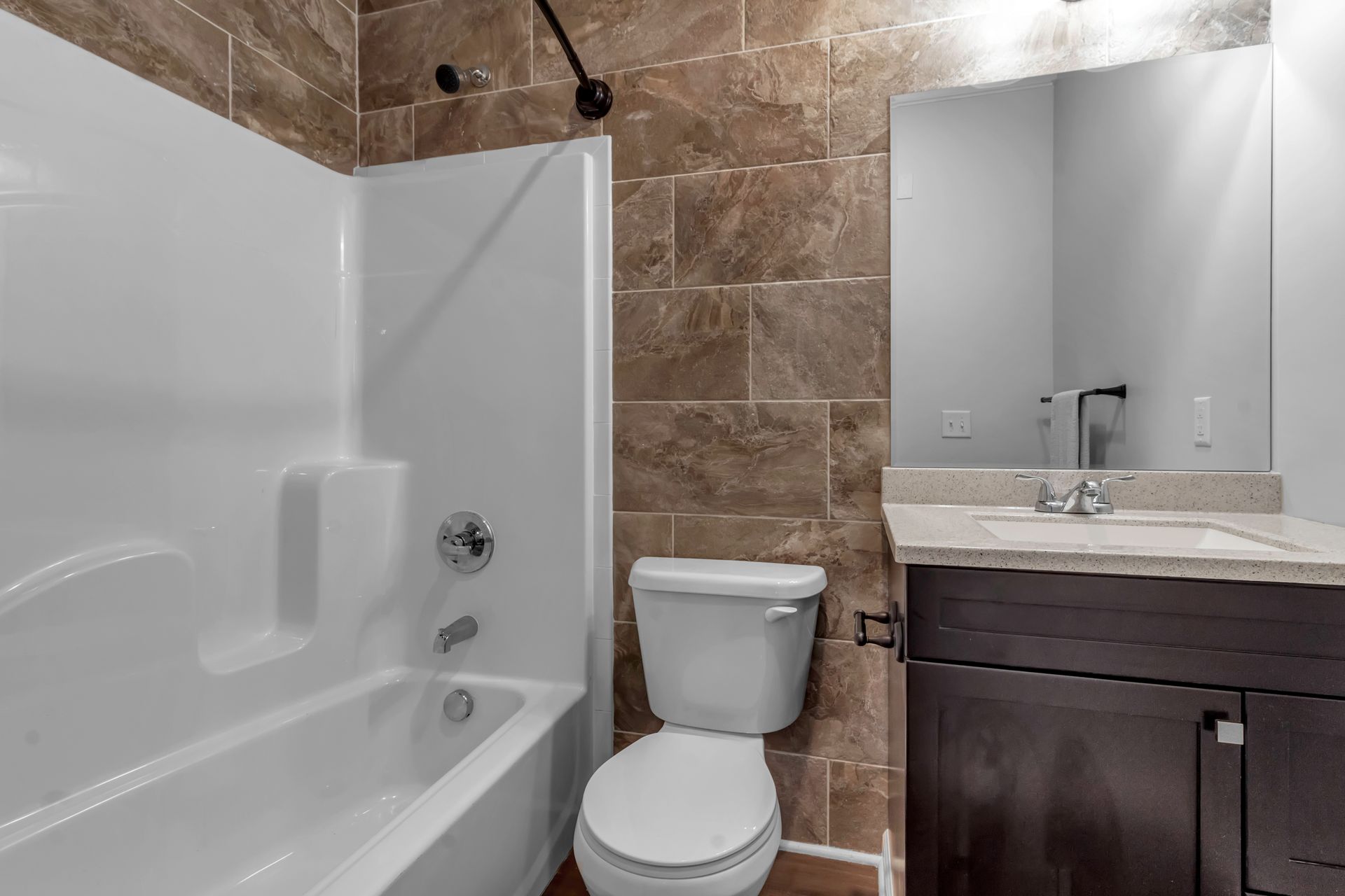 A bathroom with a toilet , sink , bathtub and mirror.