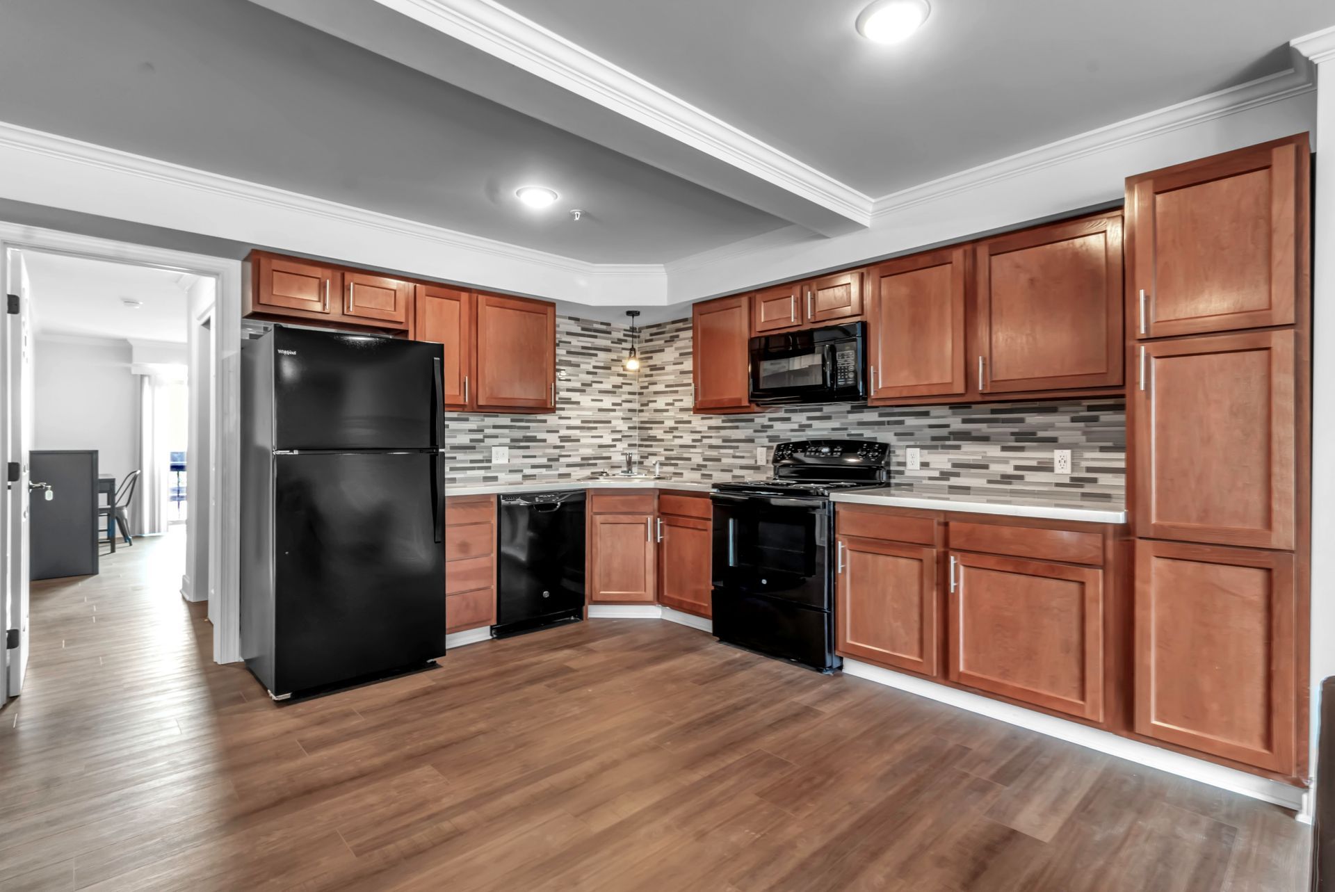 A kitchen with wooden cabinets , a black refrigerator , a stove , and a microwave.
