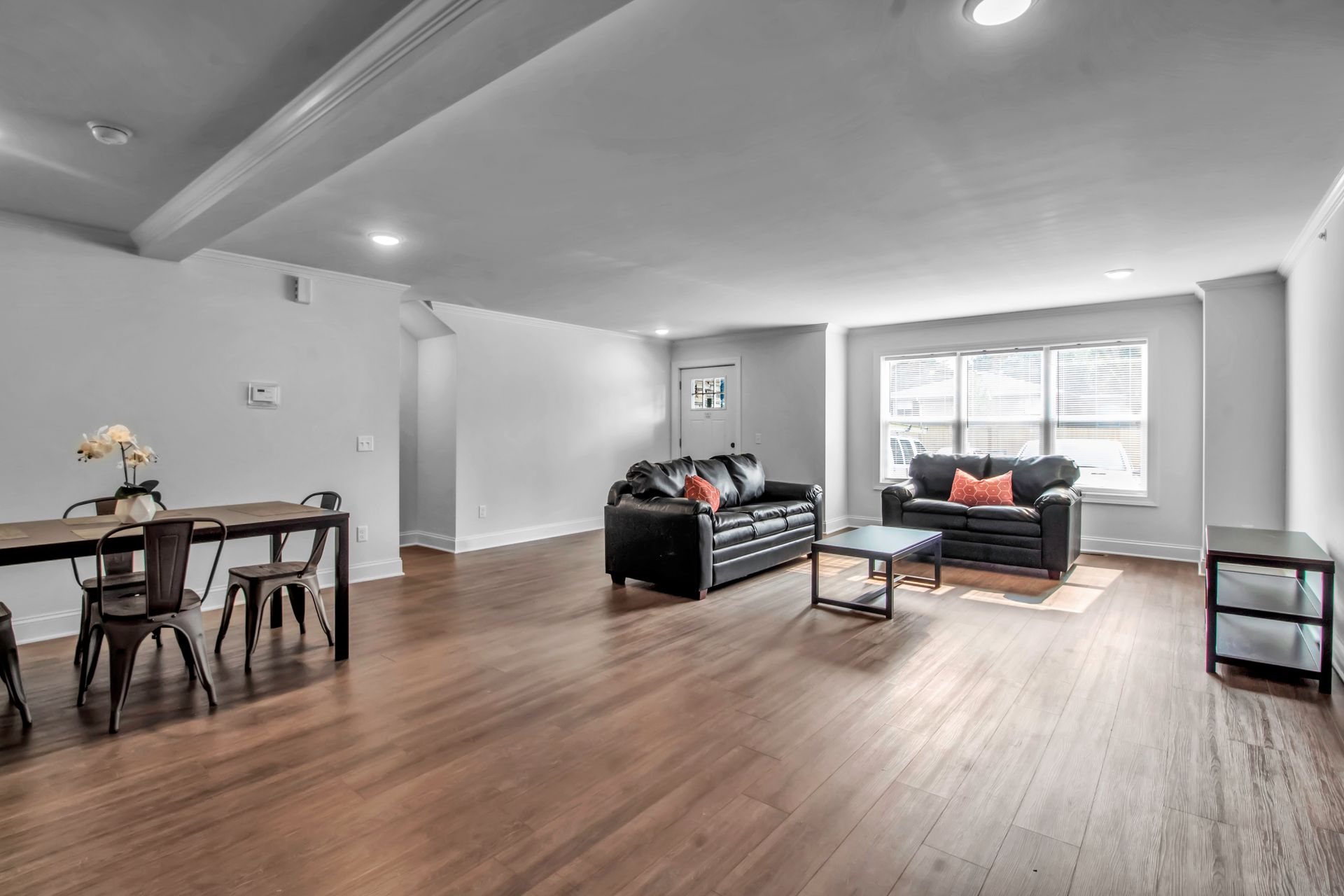 A living room with hardwood floors , a couch , a table and chairs.