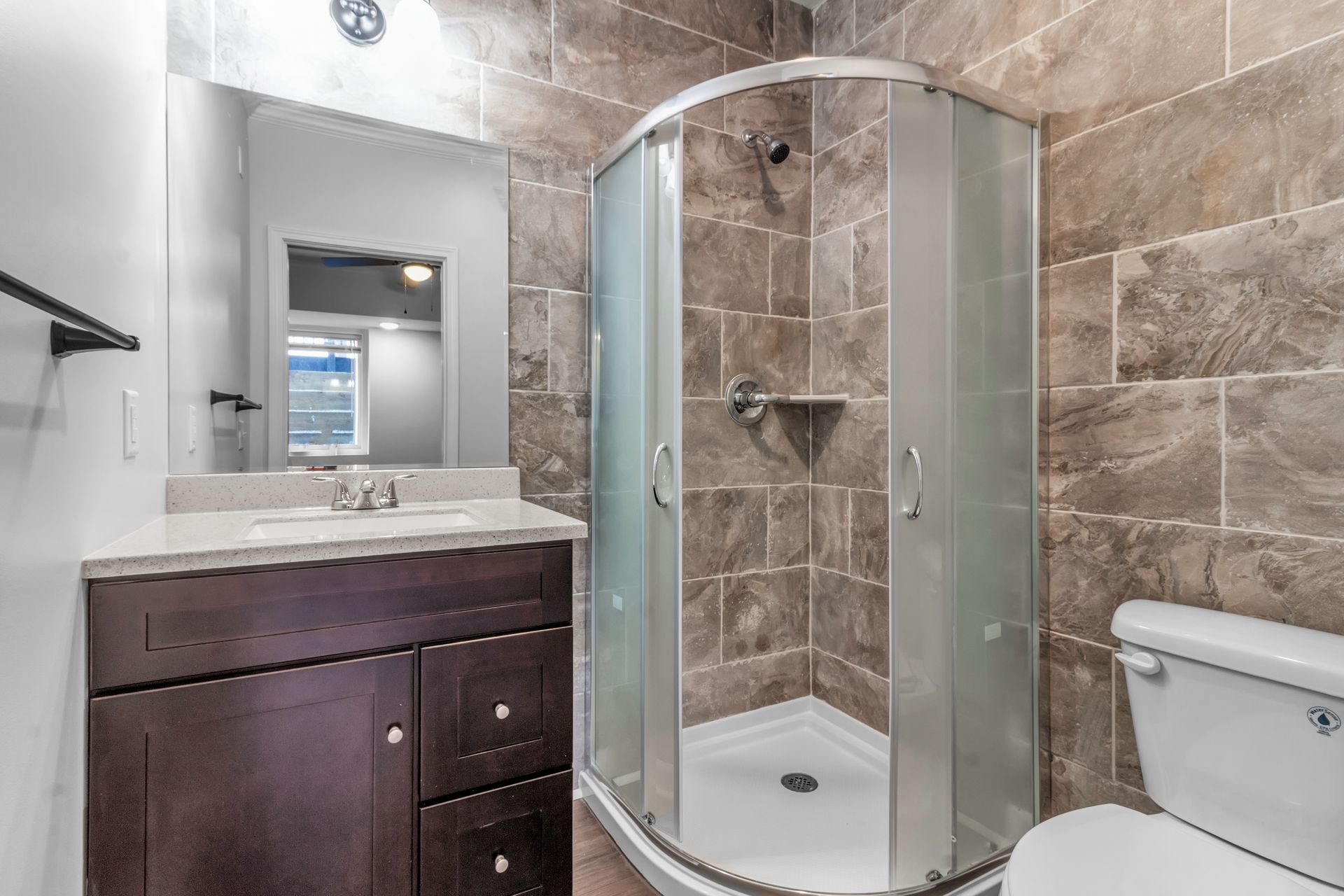 A bathroom with a toilet , sink , shower and mirror.