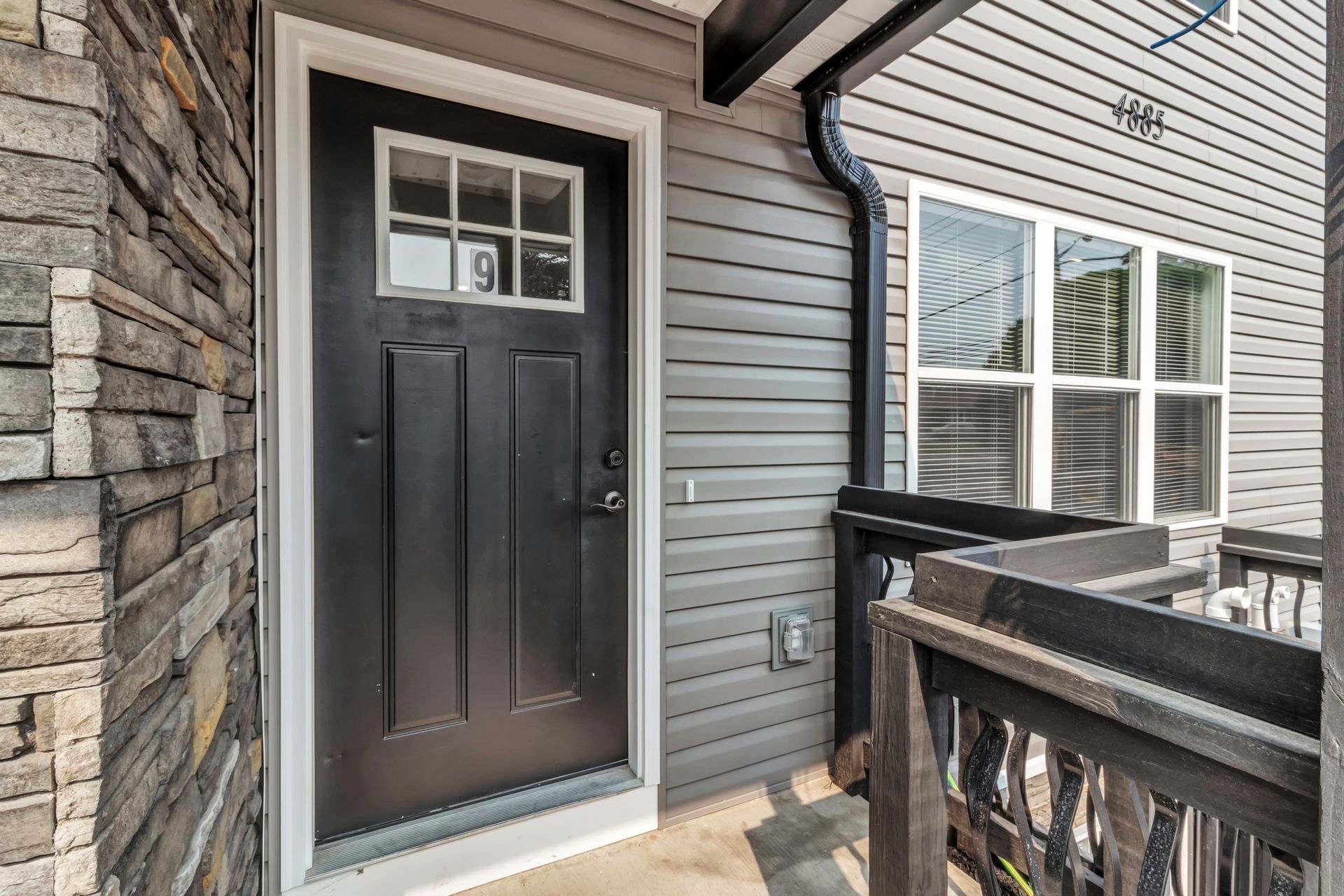 A black door with a window is on the side of a house.