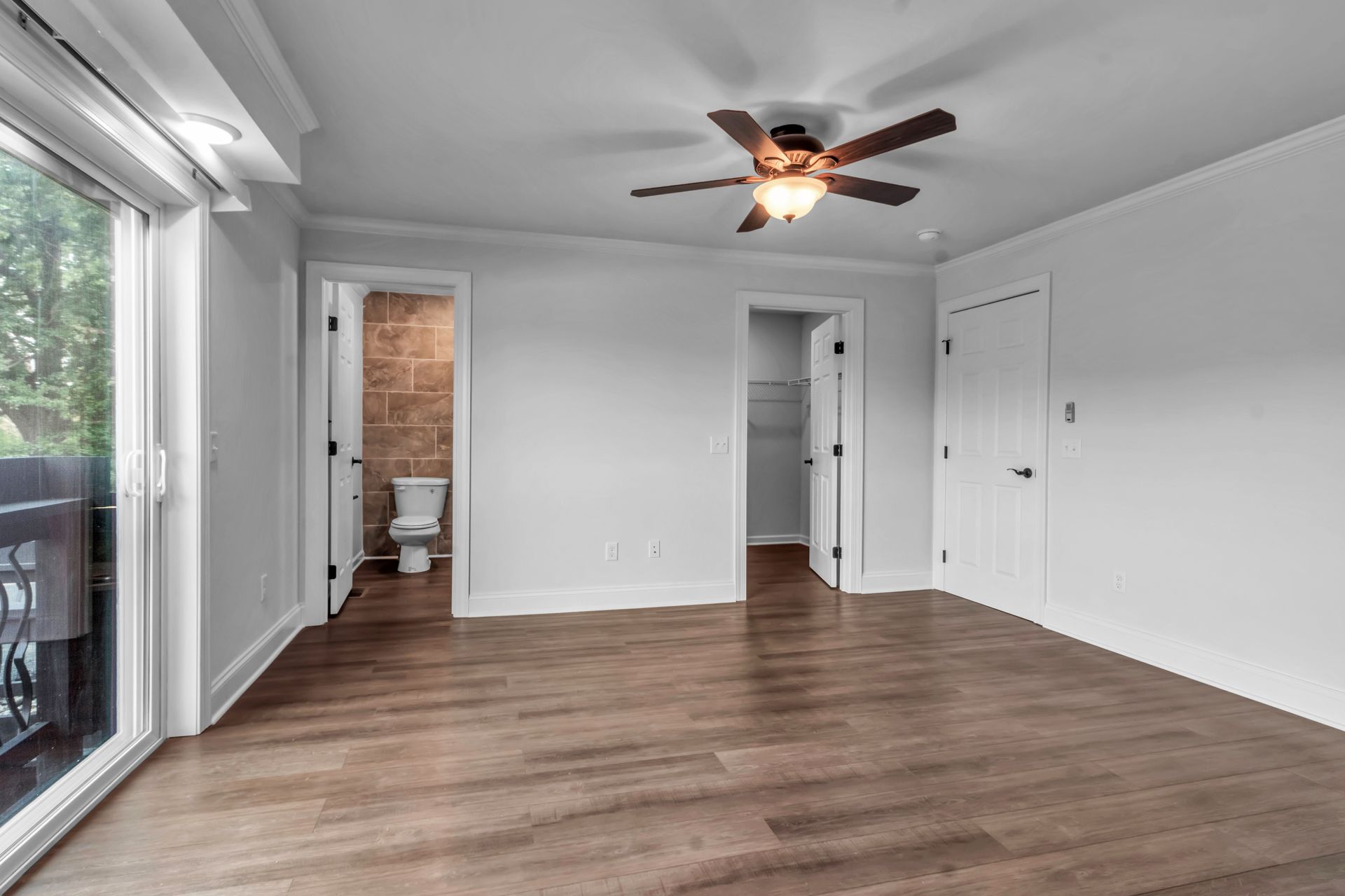 An empty room with a ceiling fan and a toilet.