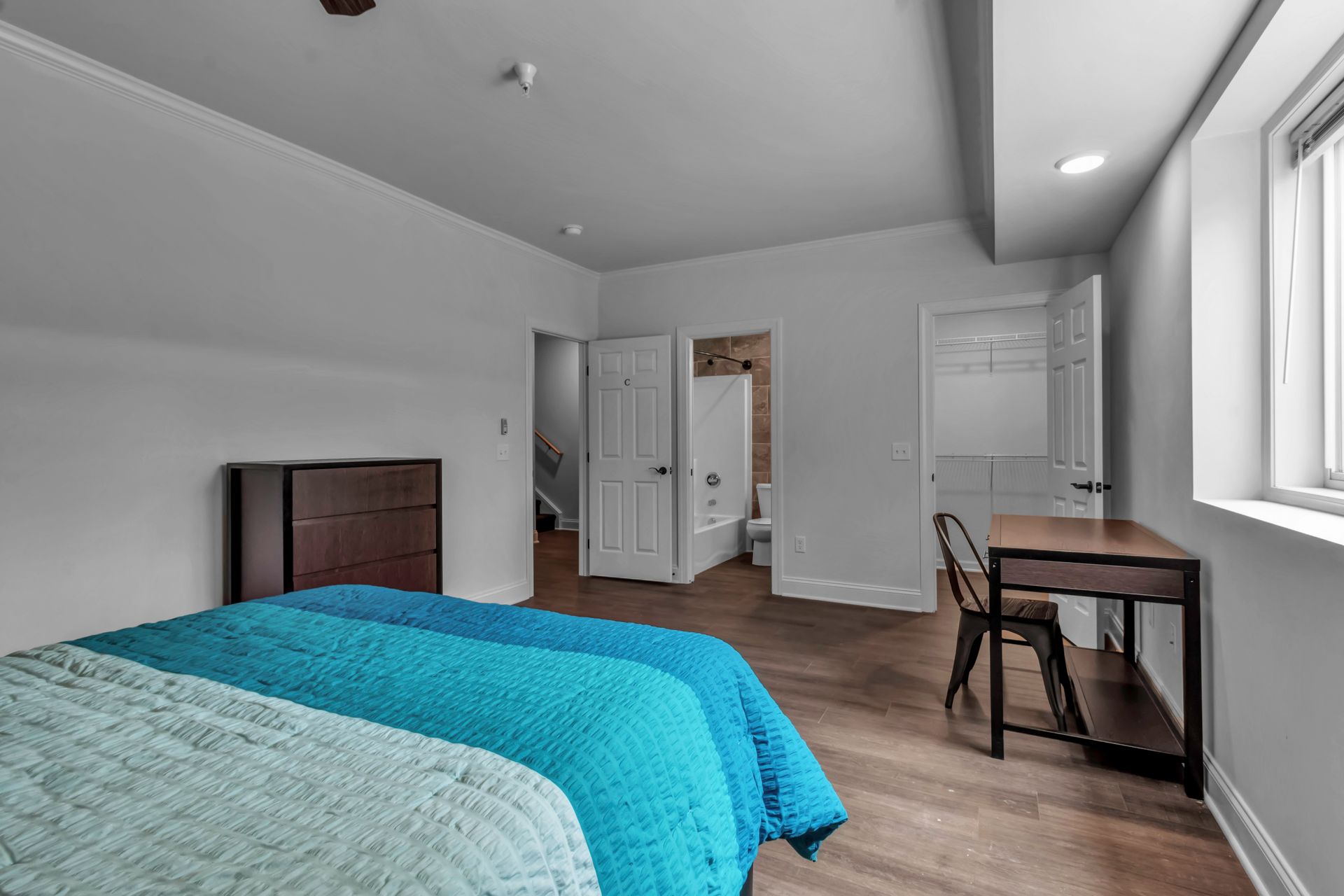 A bedroom with two beds , a desk and a window.