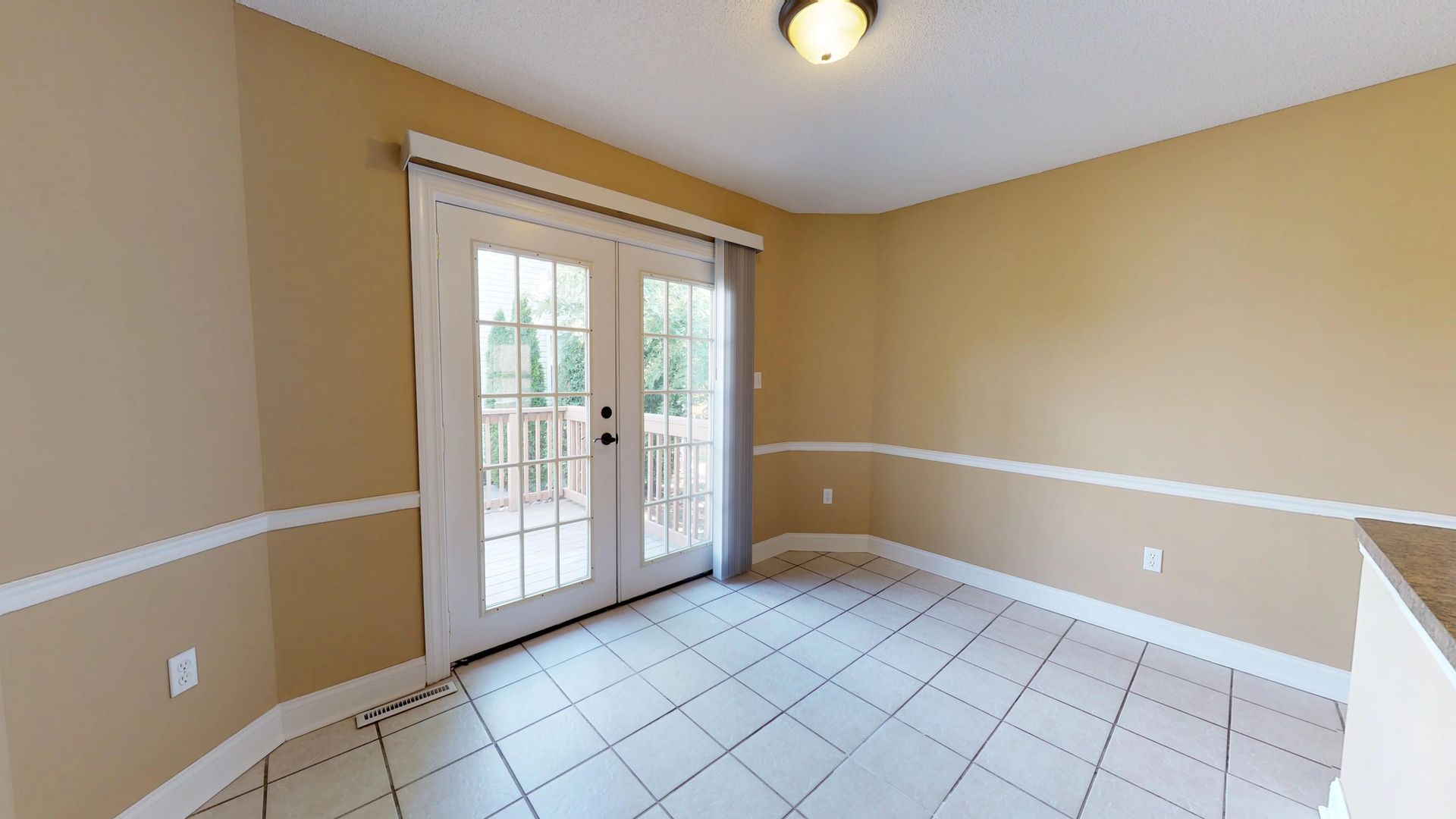 An empty room with a sliding glass door and a tile floor.