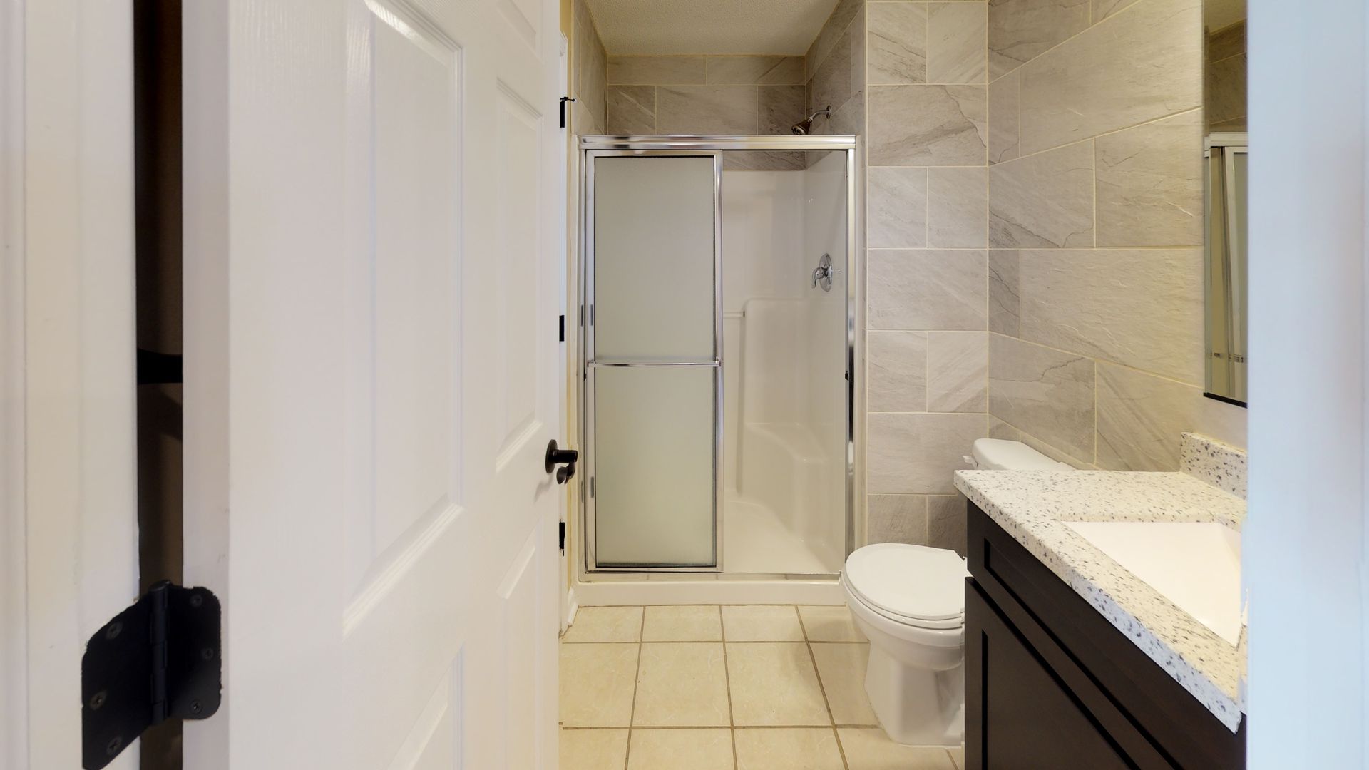 A bathroom with a toilet , sink and shower.