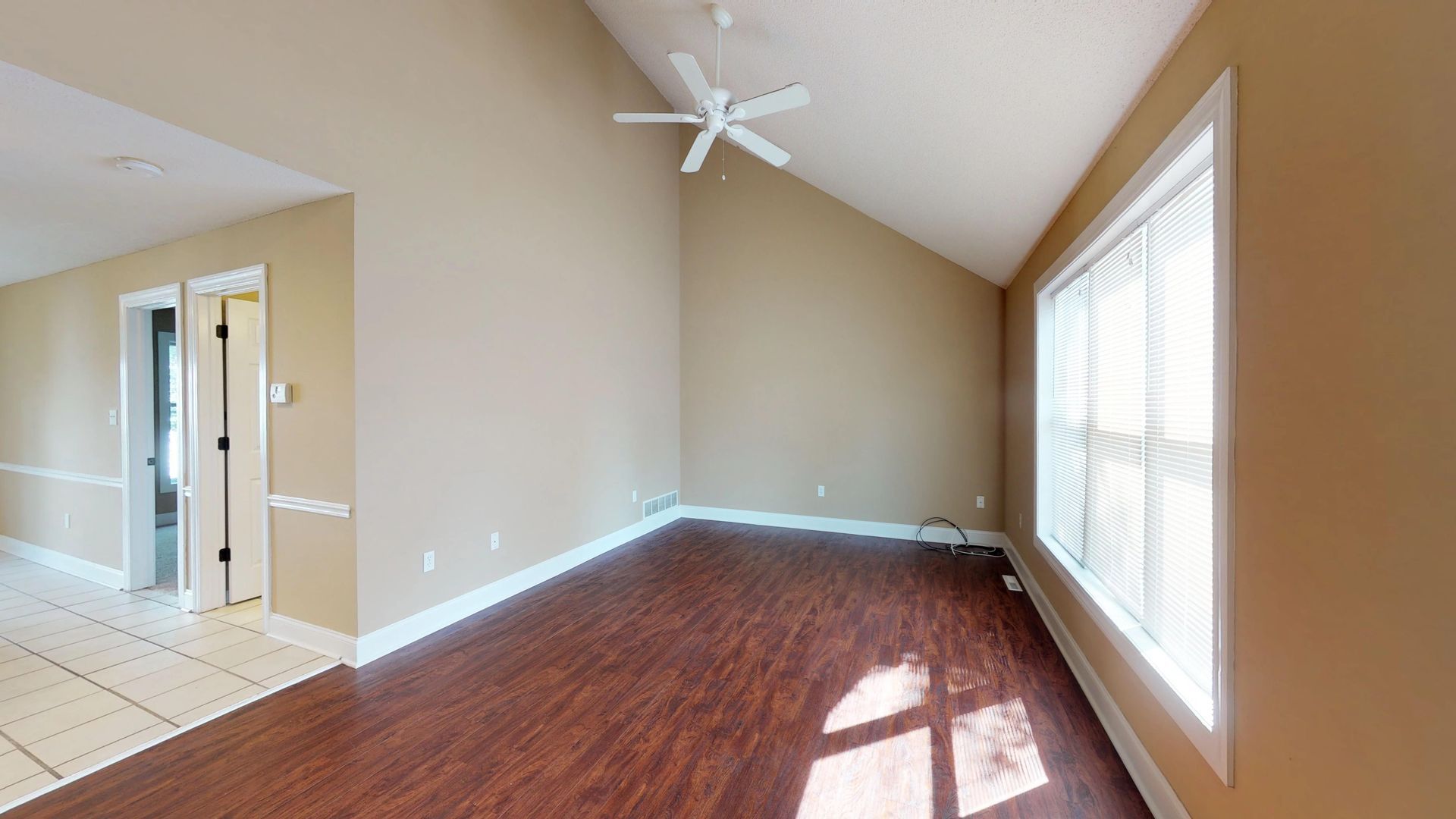 An empty living room with hardwood floors and a ceiling fan.