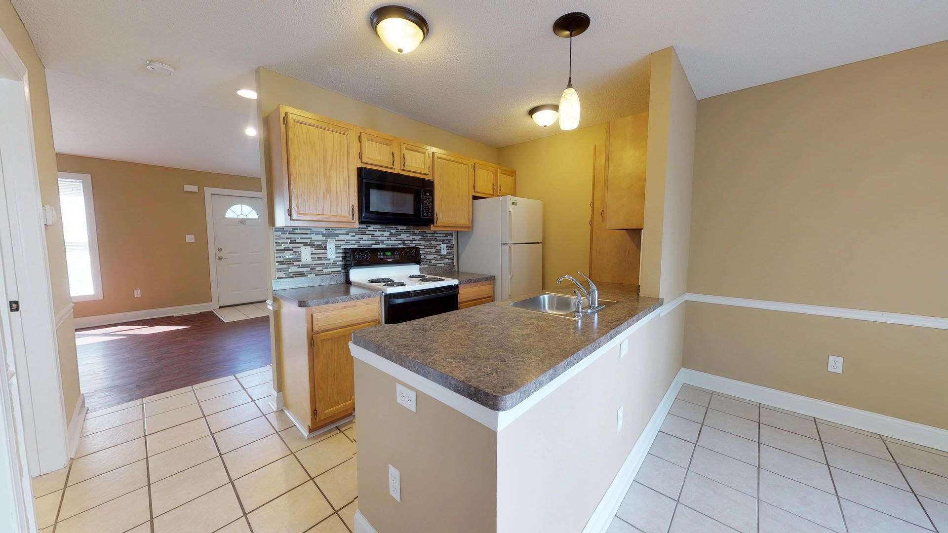 A kitchen with a refrigerator , stove , microwave and sink.