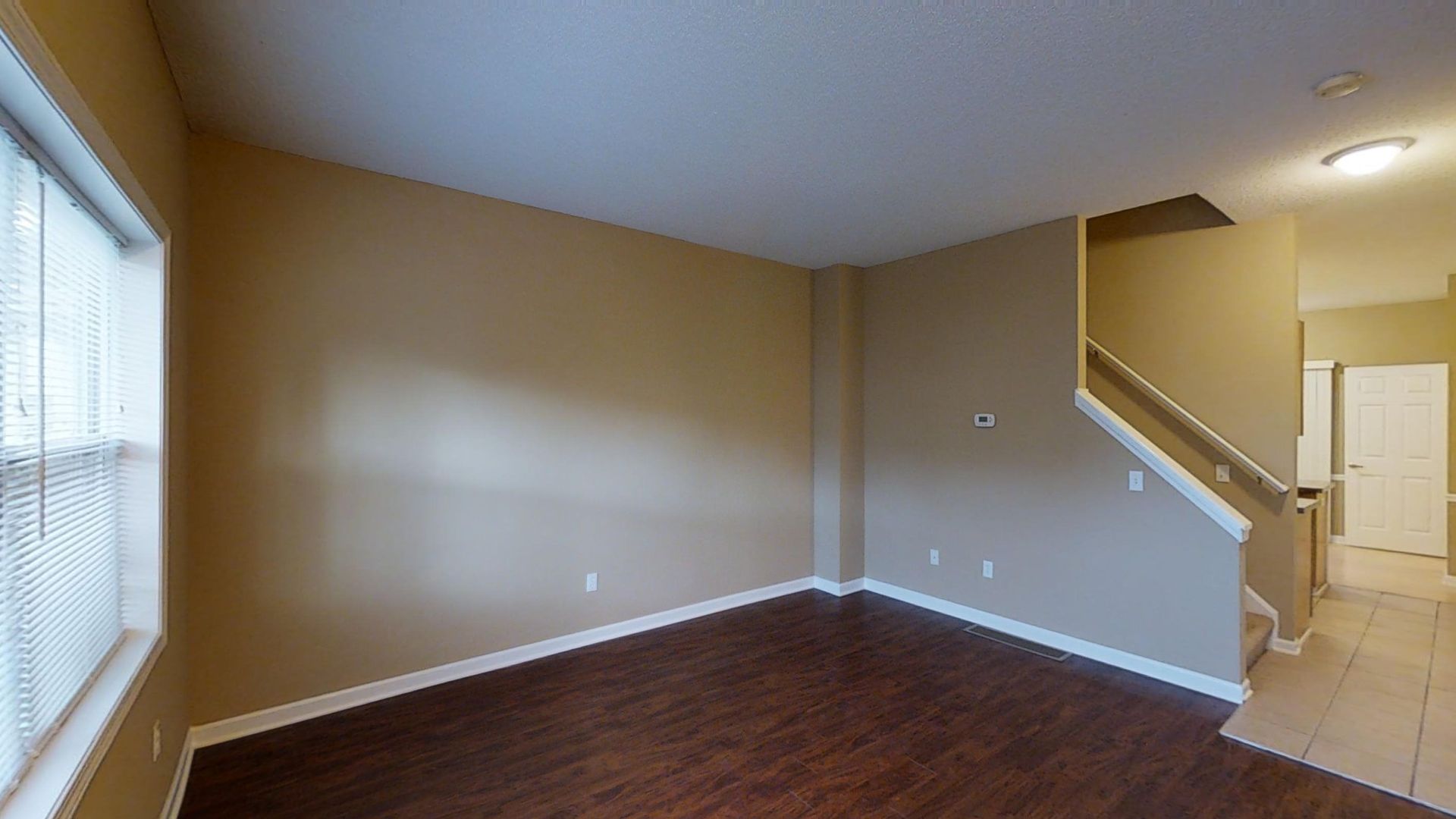 An empty living room with hardwood floors and stairs in a house.