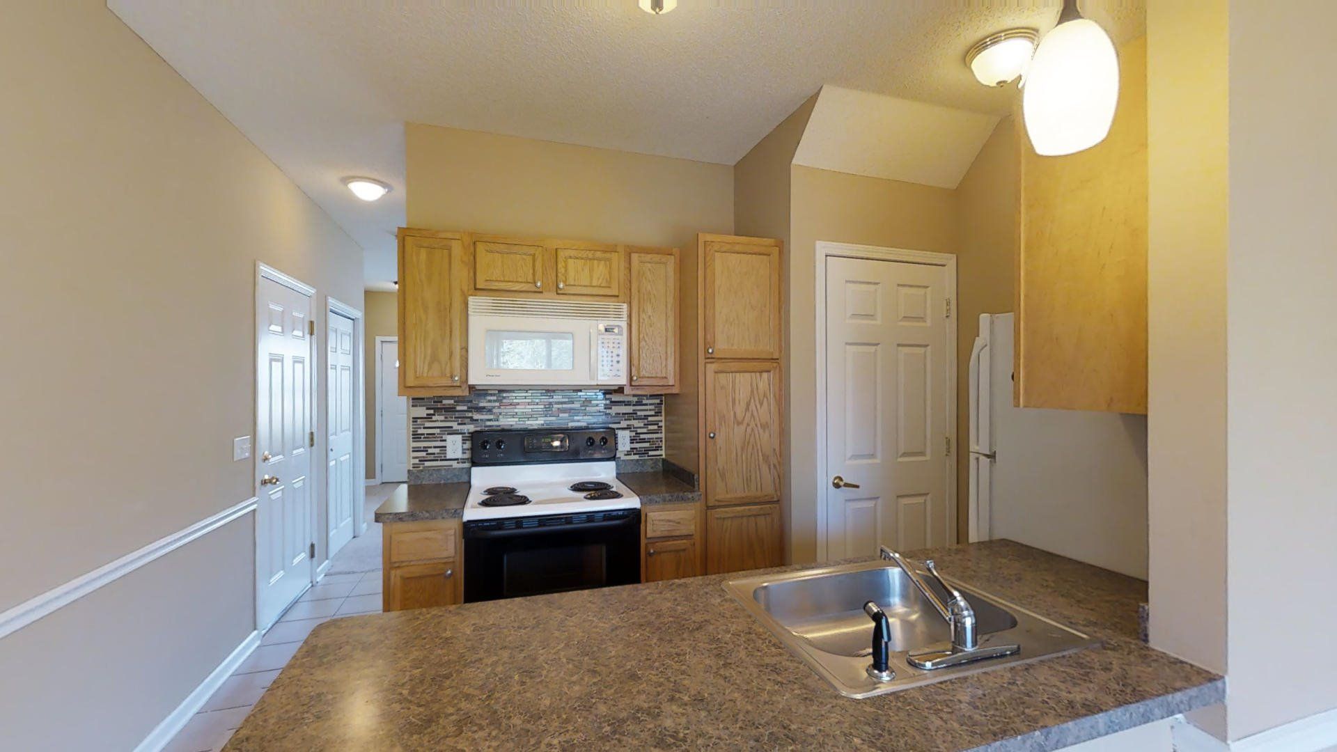 A kitchen with a sink , stove , microwave and cabinets.