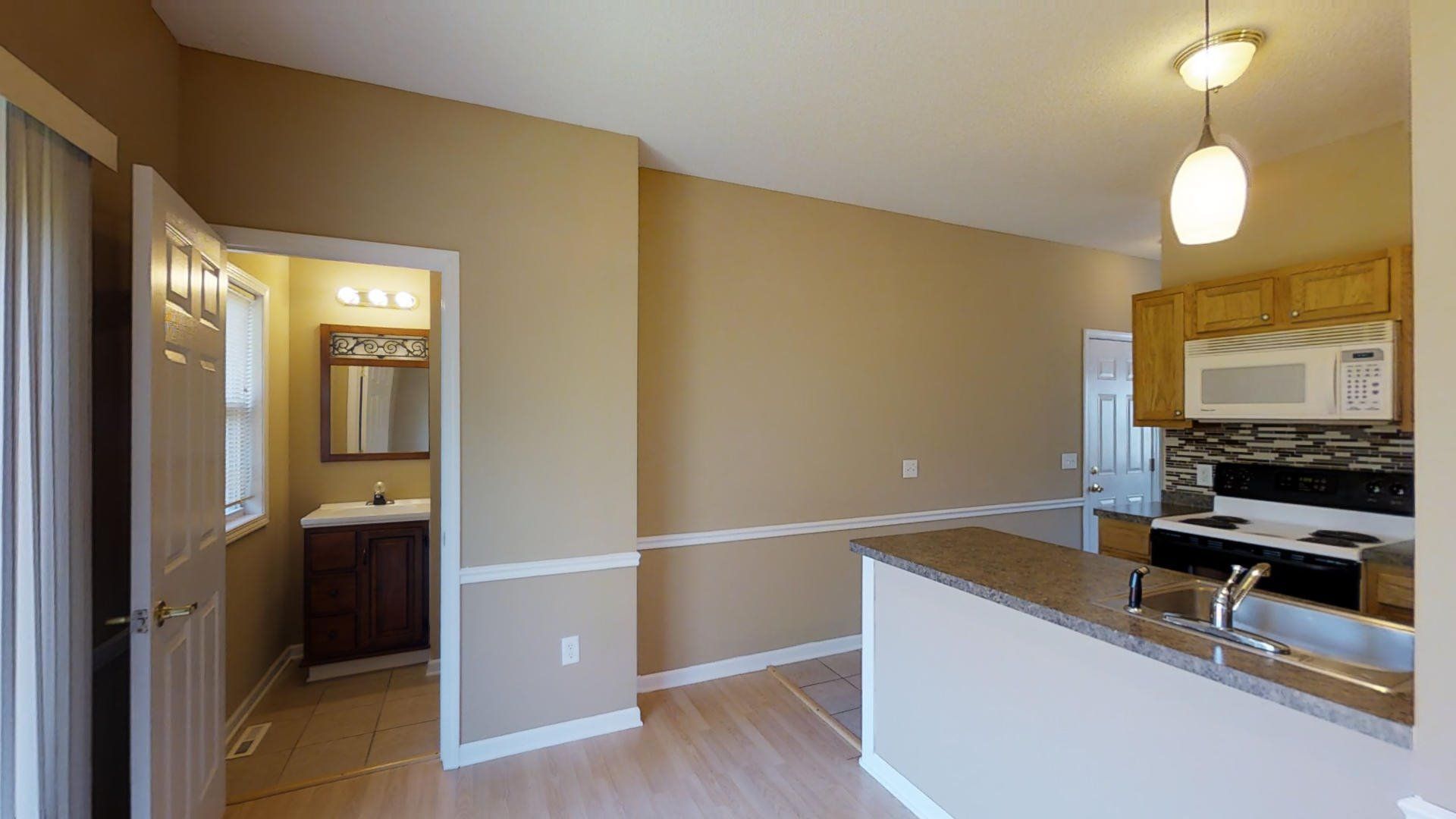 A kitchen with a sink , stove and microwave in a house.
