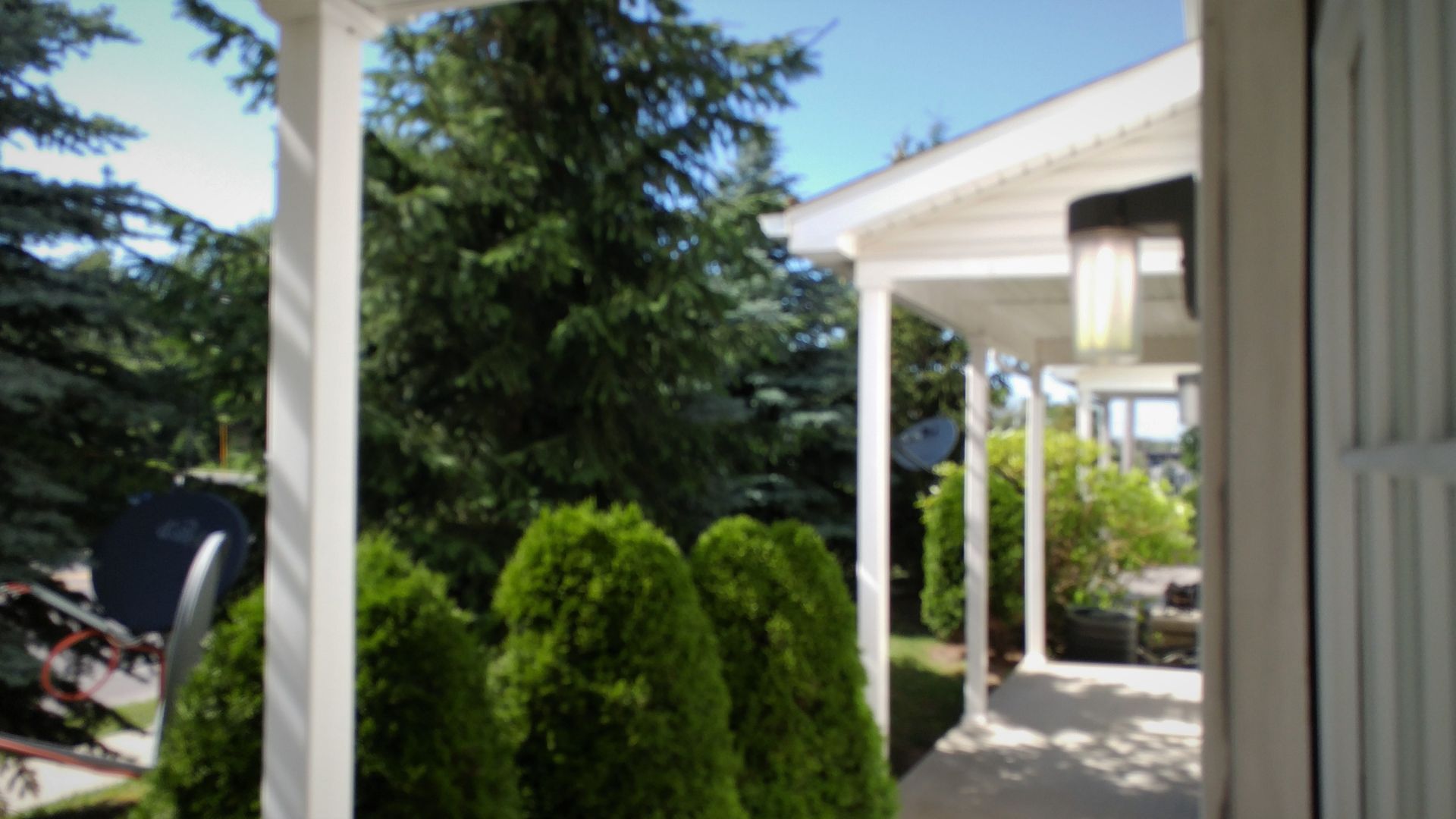 A white house with a porch and trees in the background.