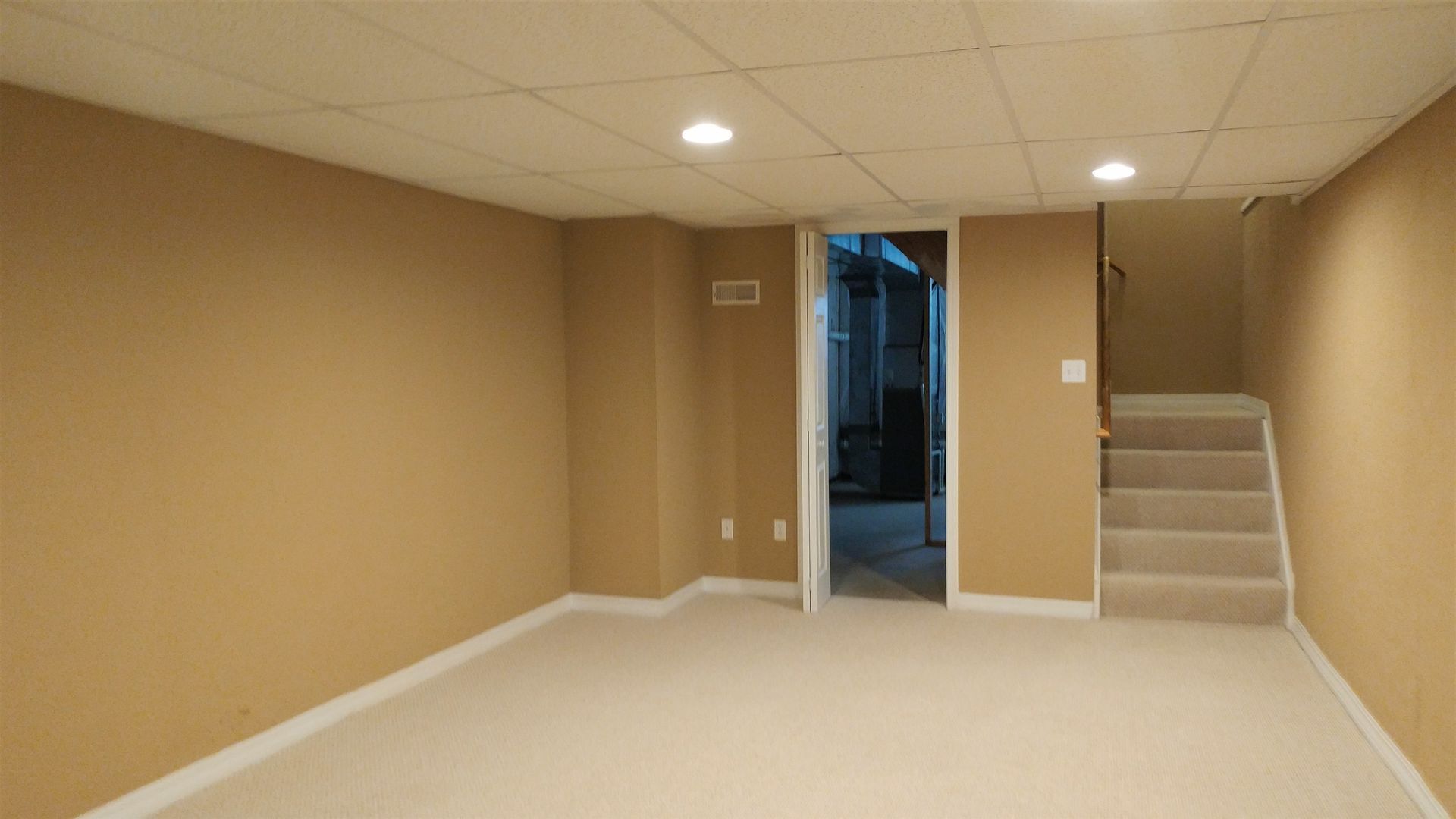 An empty basement with stairs leading up to the second floor.