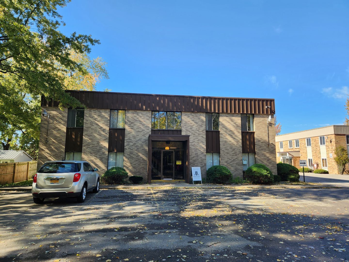 A car is parked in front of a large brick building.