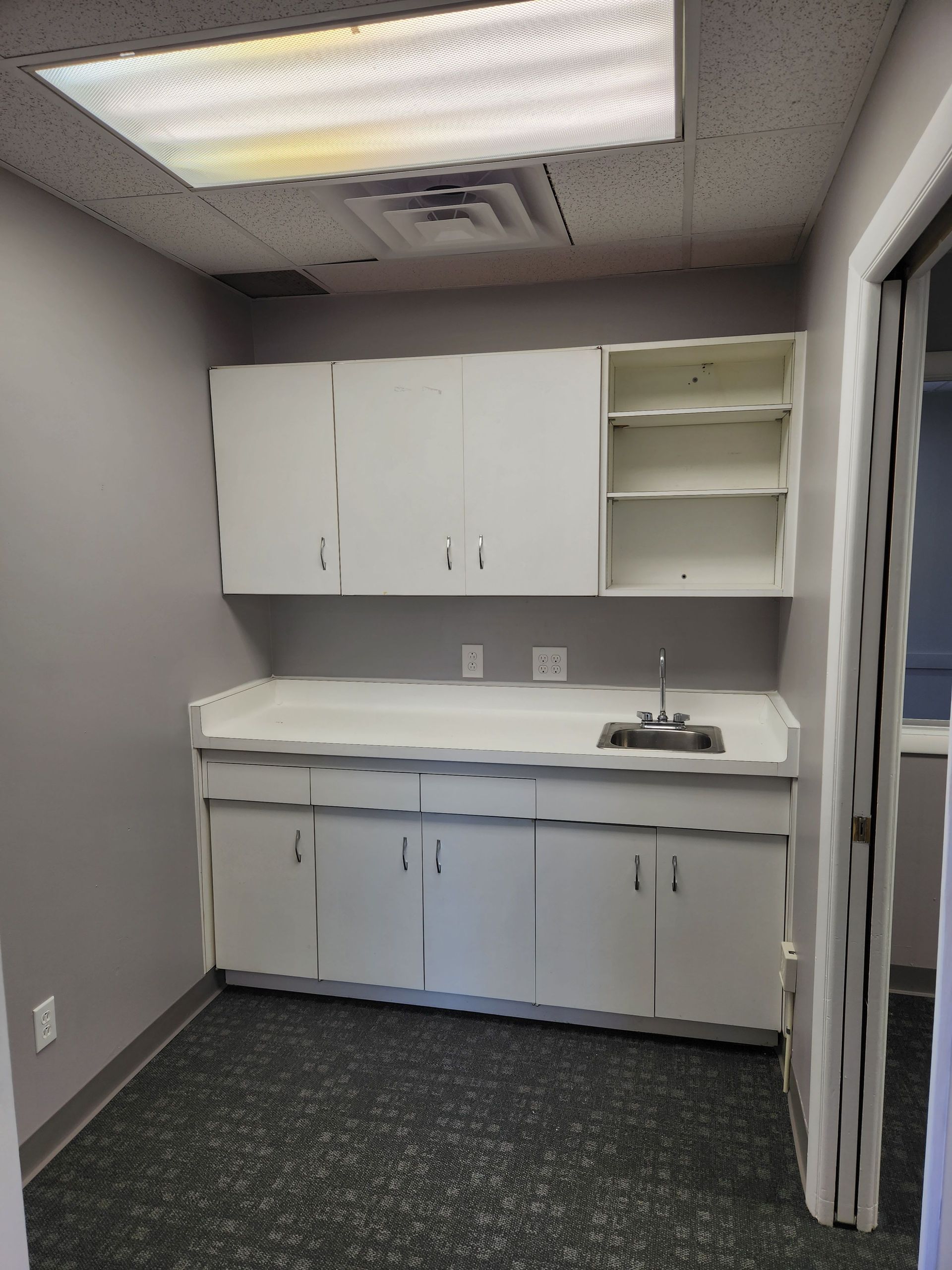 An empty kitchen with white cabinets and a sink