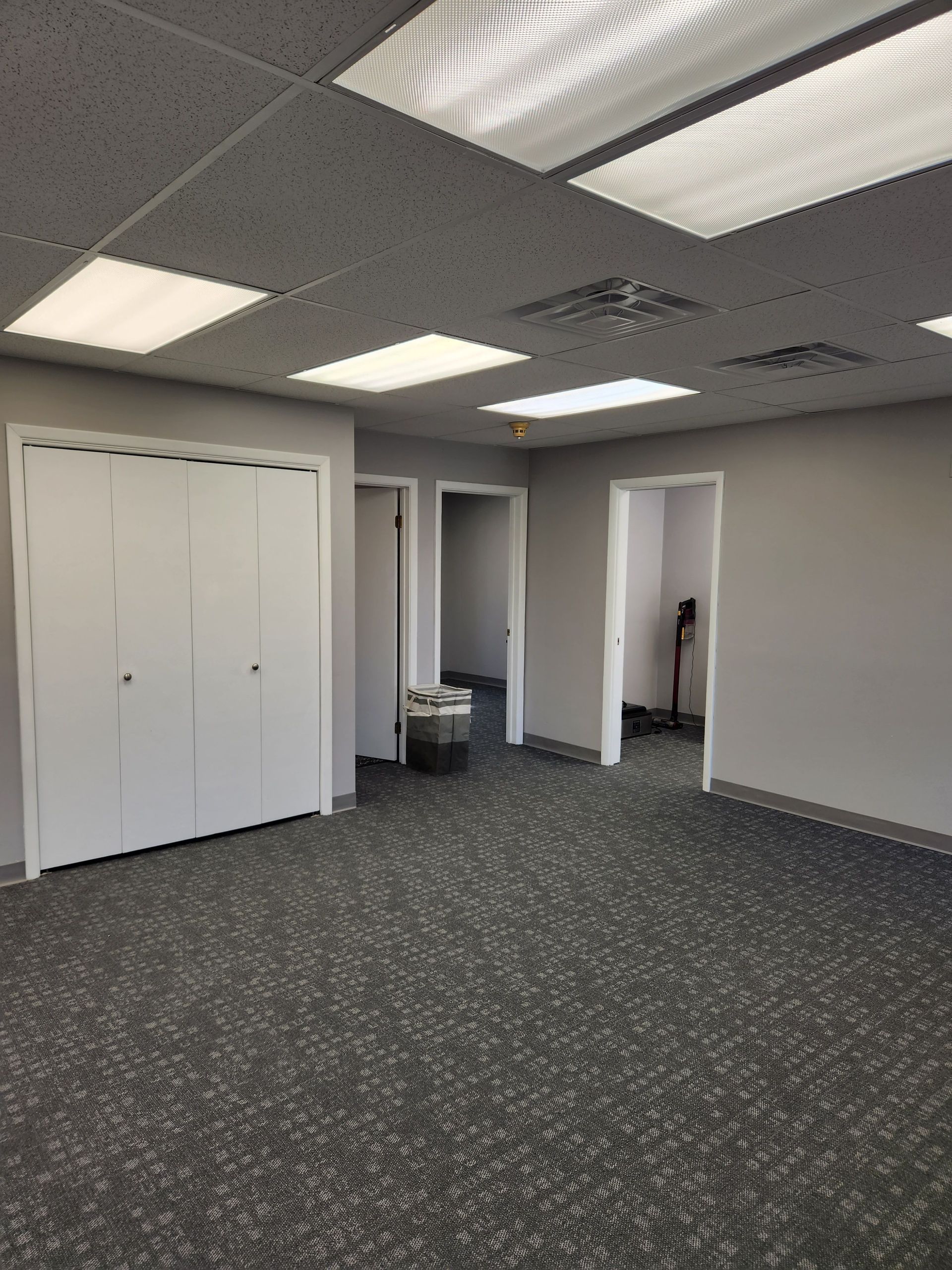 A large empty room with a carpeted floor and white walls.
